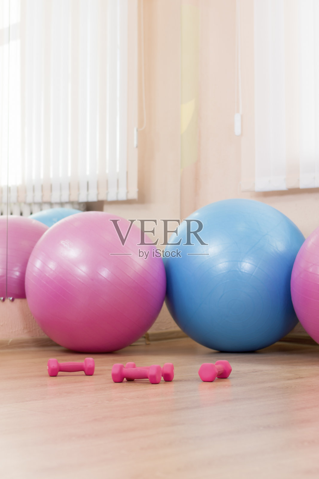 室内运动健身中心的地板上有三个大的Fitballs和杠铃。垂直的形象定位照片摄影图片