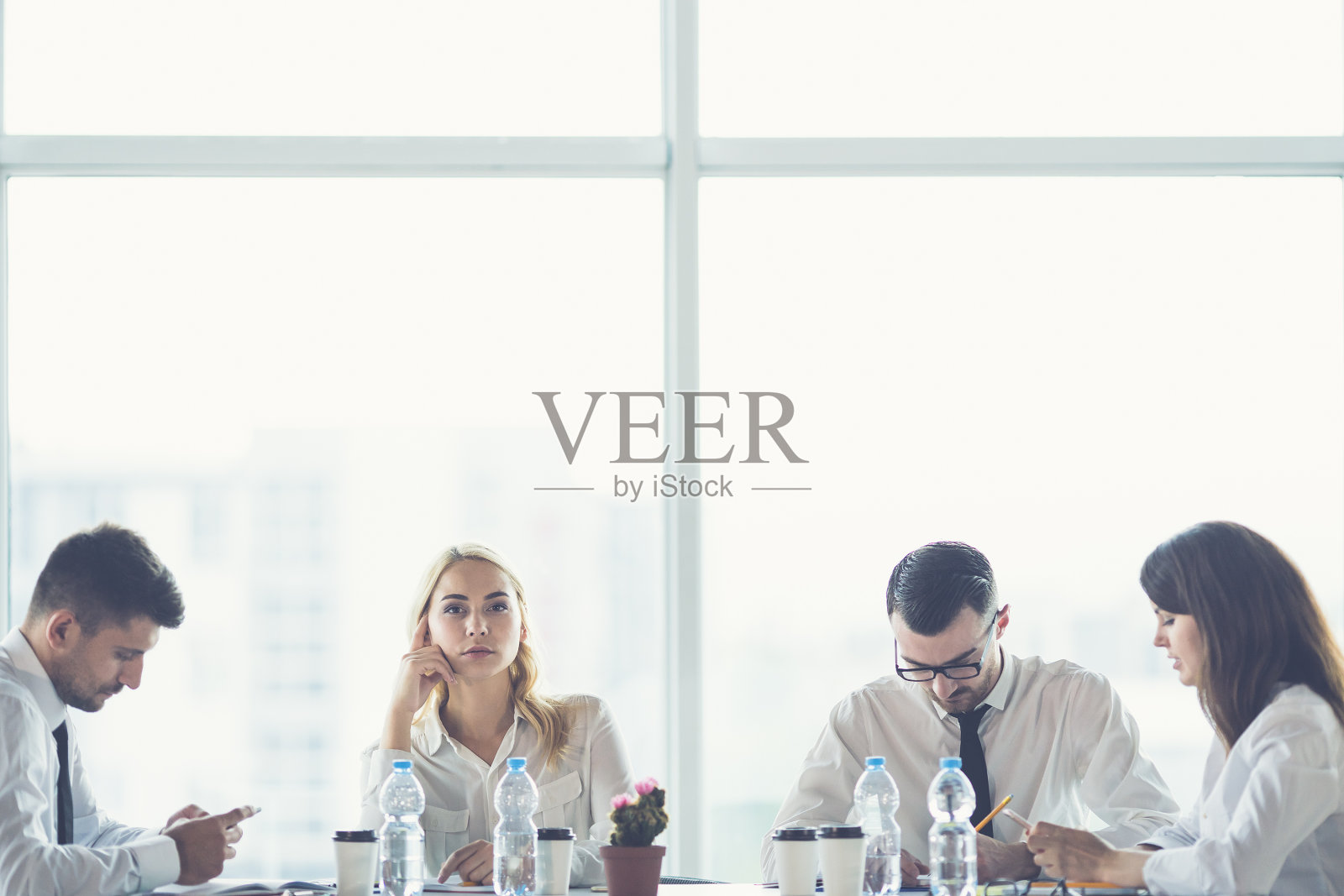 四个商务人士坐在办公室的桌子旁照片摄影图片