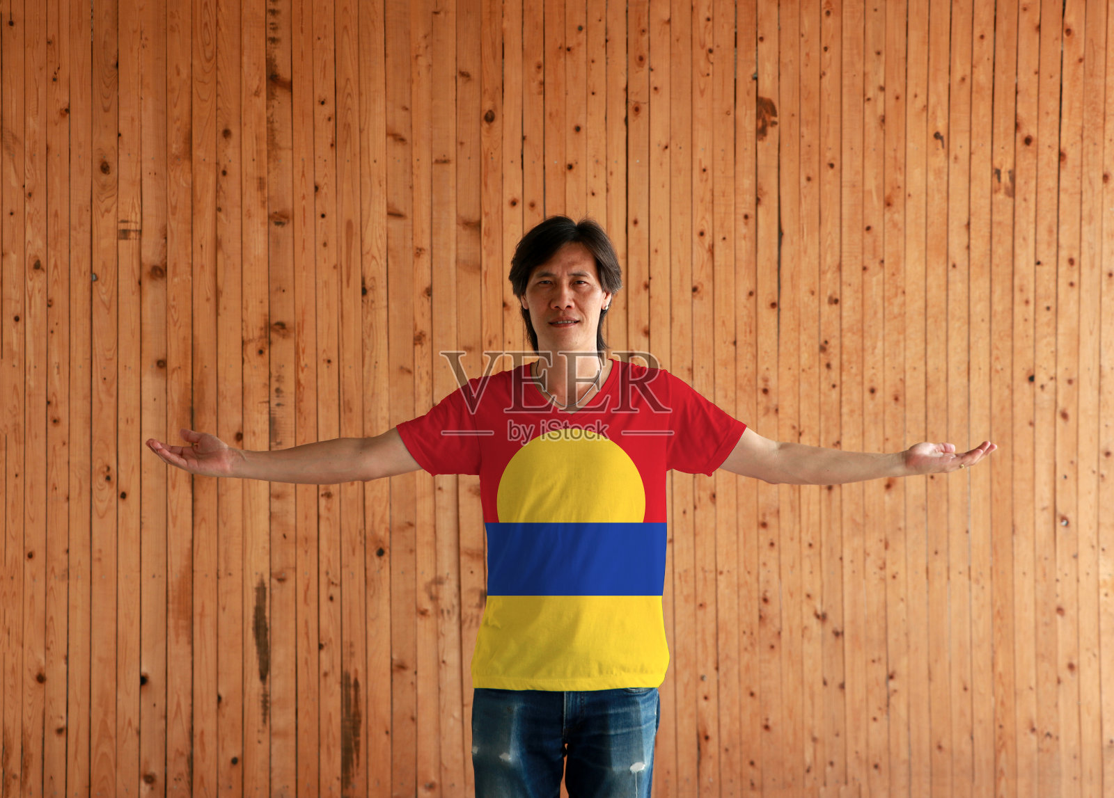 男子身穿美国小离岛旗色衬衫，双臂张开站在木墙的背景上。照片摄影图片