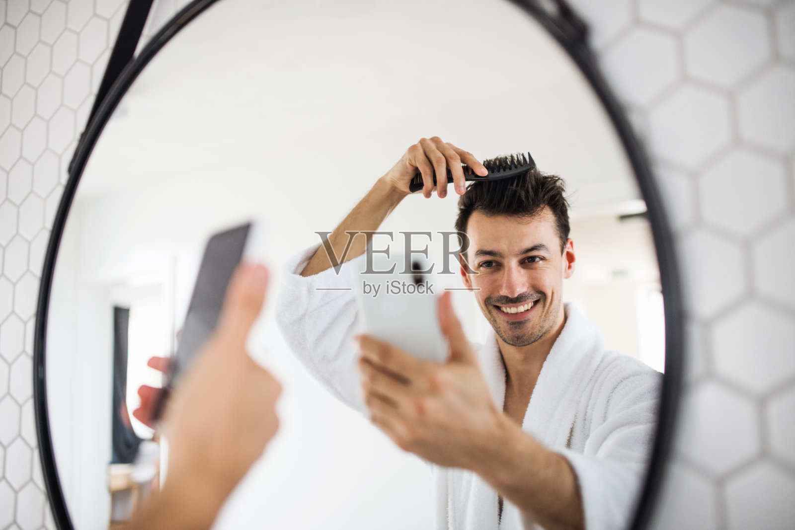 一个年轻人早上在浴室梳头发，自拍。照片摄影图片