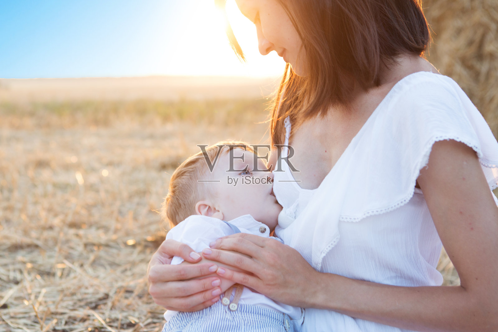 美丽快乐的母亲在户外给她的宝贝儿子喂奶。照片摄影图片