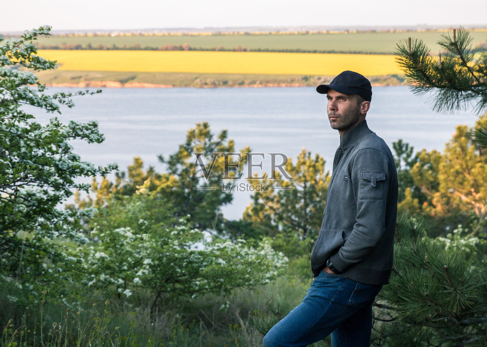 戴着帽子的乡下人欣赏湖面上的夕阳和黄澄澄的田野照片摄影图片