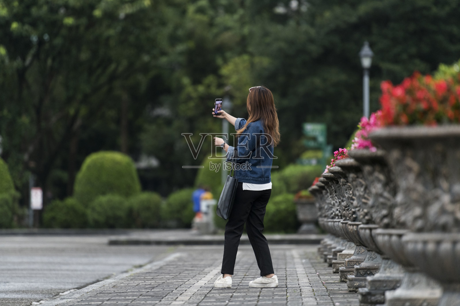 一名年轻女子在被绿树环绕的传统城市广场上转身自拍照片摄影图片