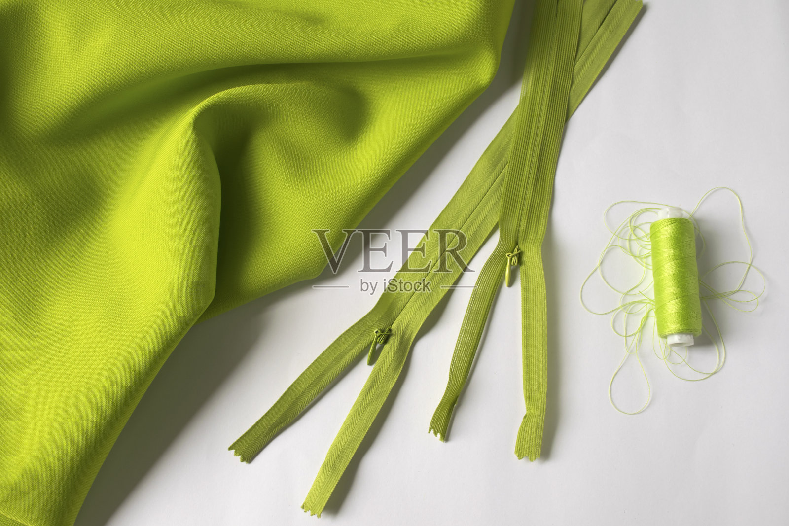 “r”n用于缝纫和针线活的工具。绿色的线和绿色的织物。照片摄影图片