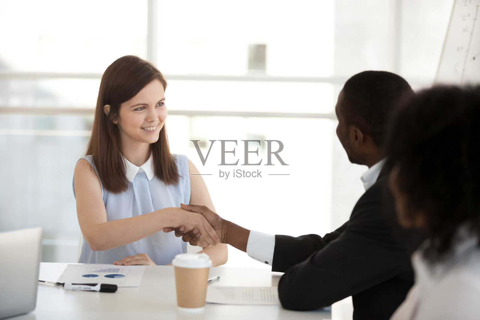 快乐的年轻女商人与非裔美国同事握手照片摄影图片