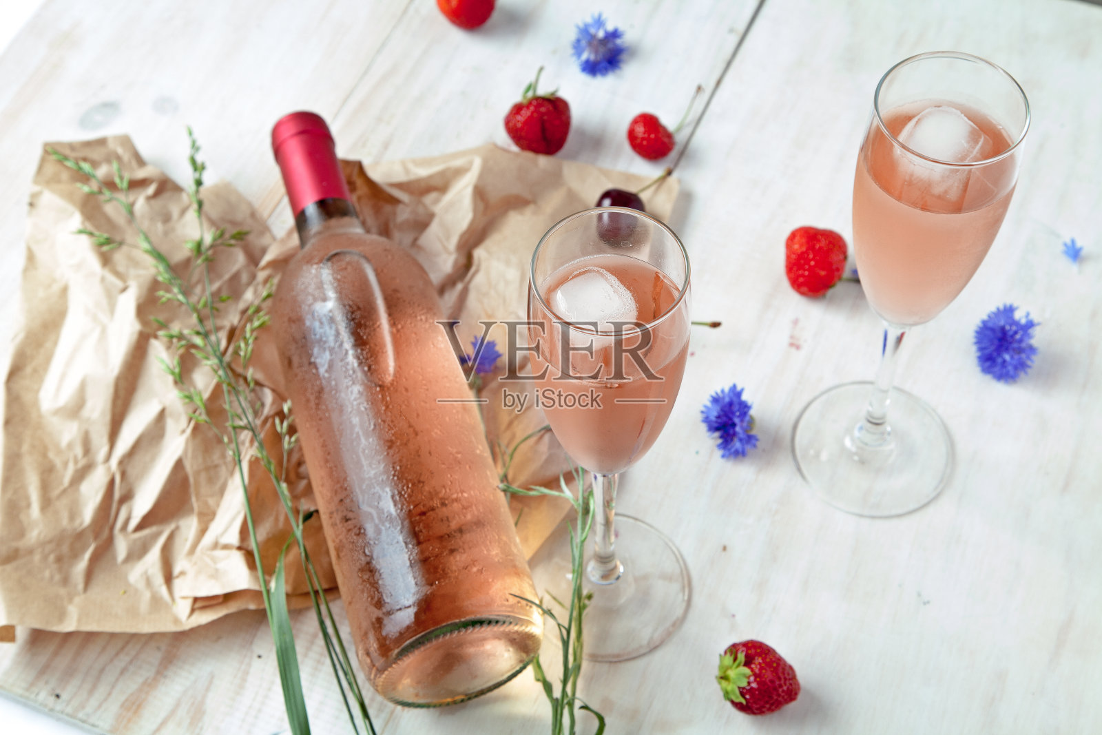 白色木桌上质朴的木板上放着一瓶粉红色的葡萄酒和酒杯照片摄影图片