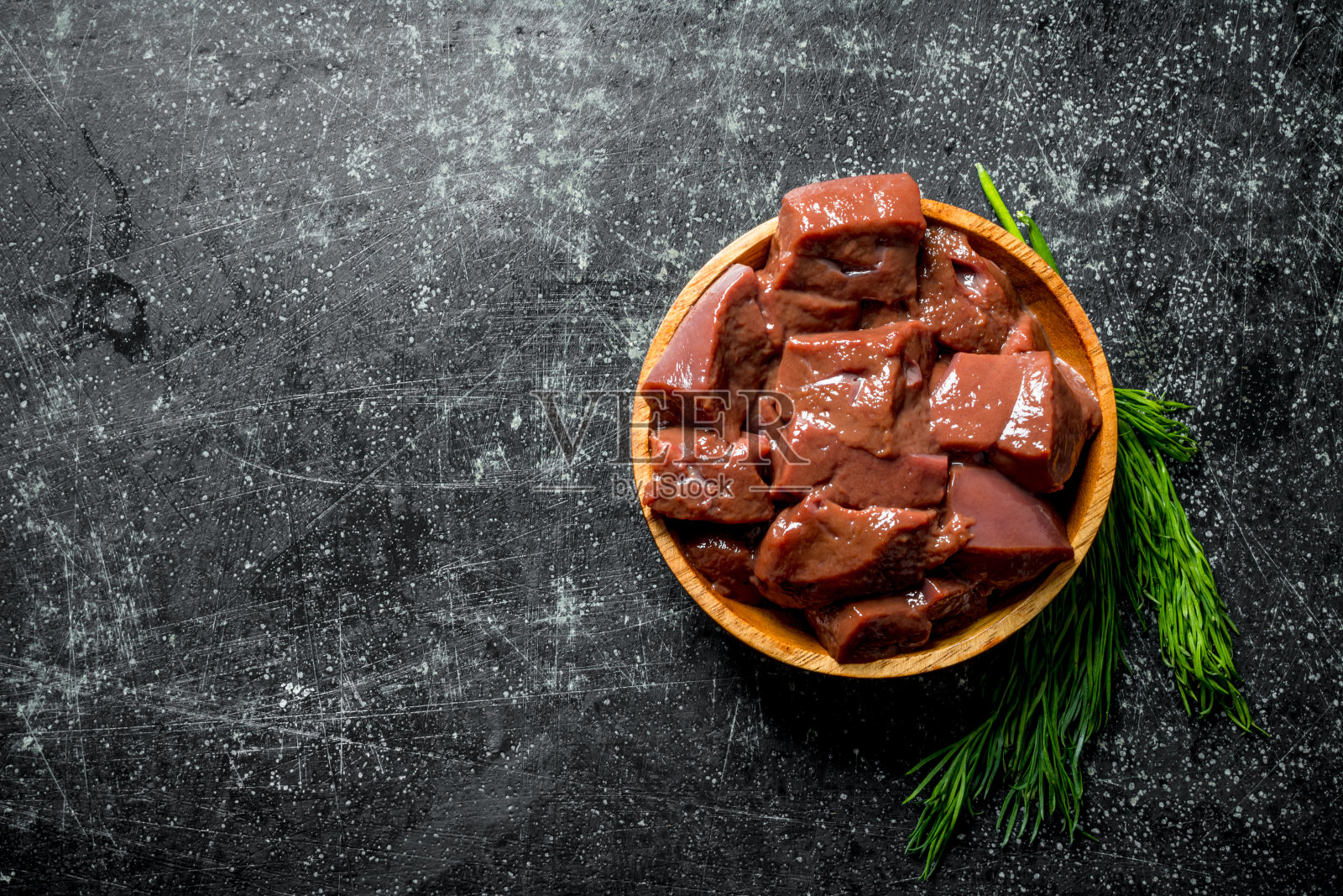 几片生肝放在一盘小茴香上。照片摄影图片