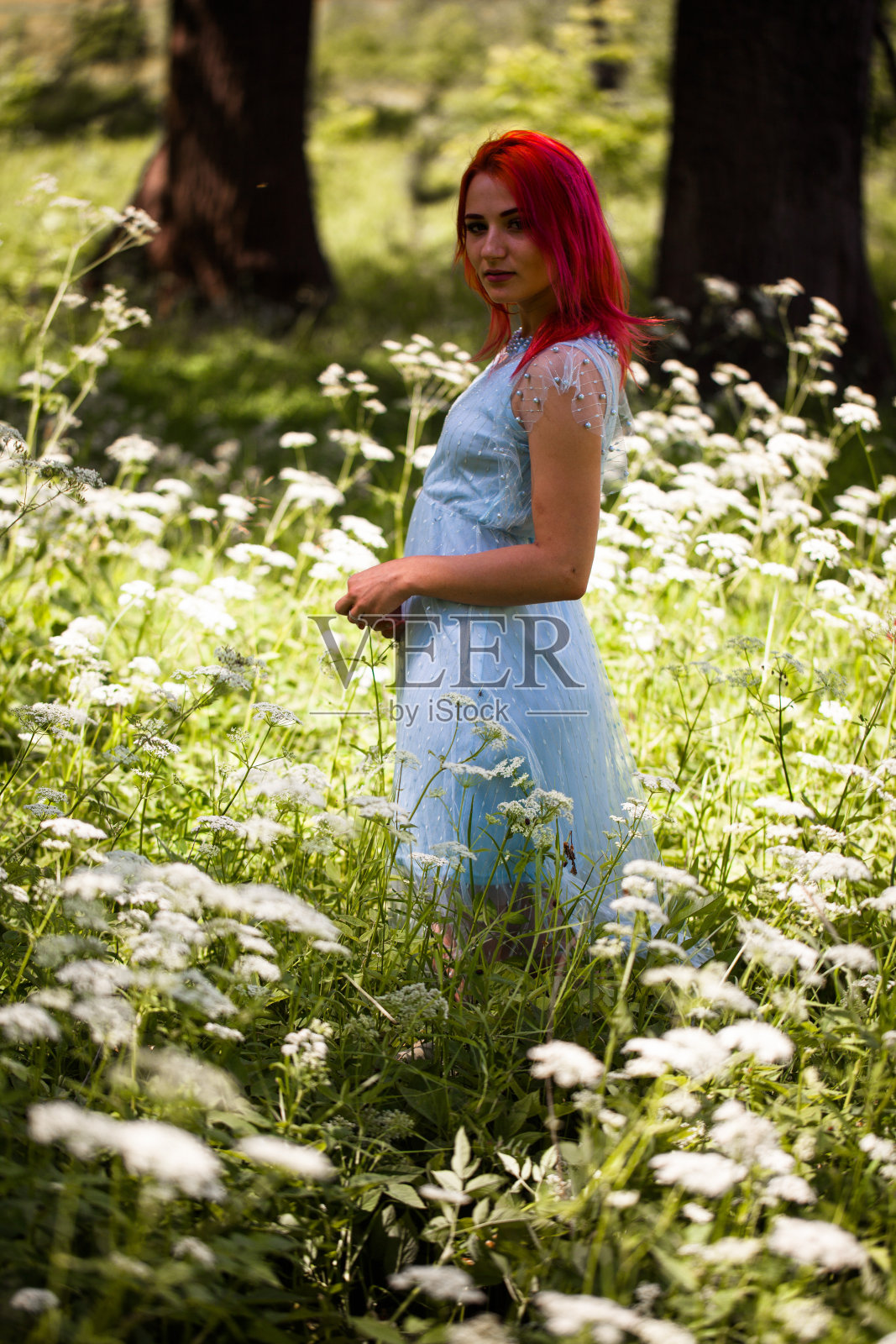 年轻女子在田野野花丛中，头发鲜艳照片摄影图片