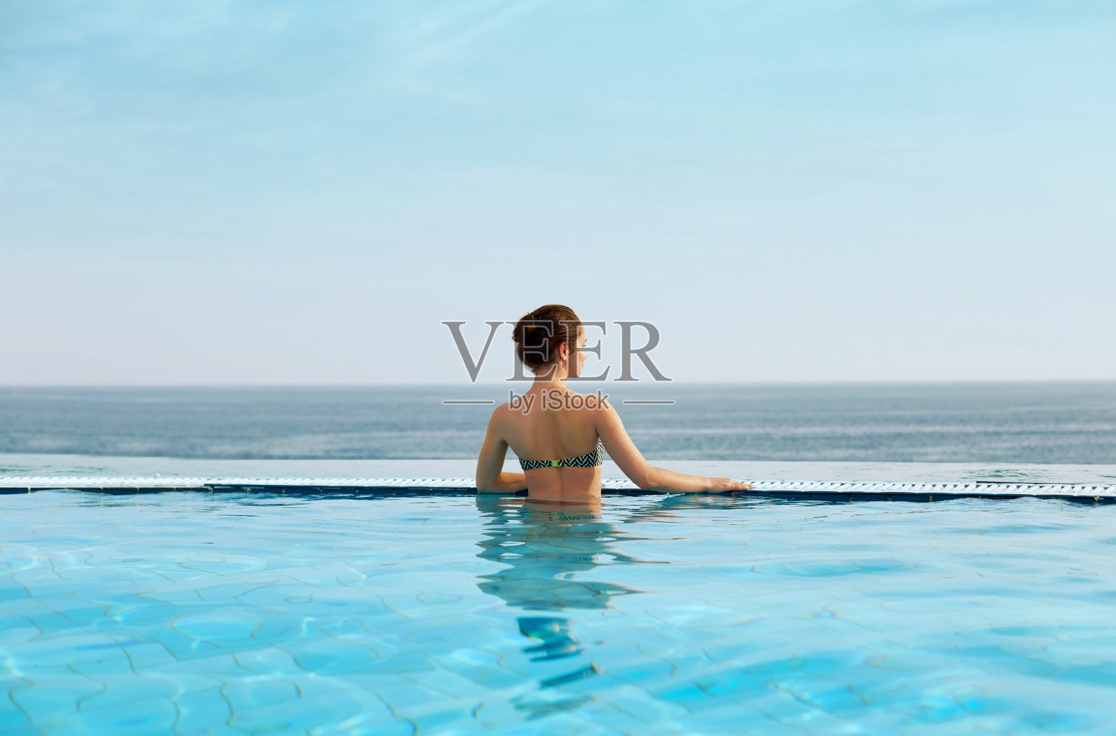 女人享受在游泳池和看放松照片摄影图片
