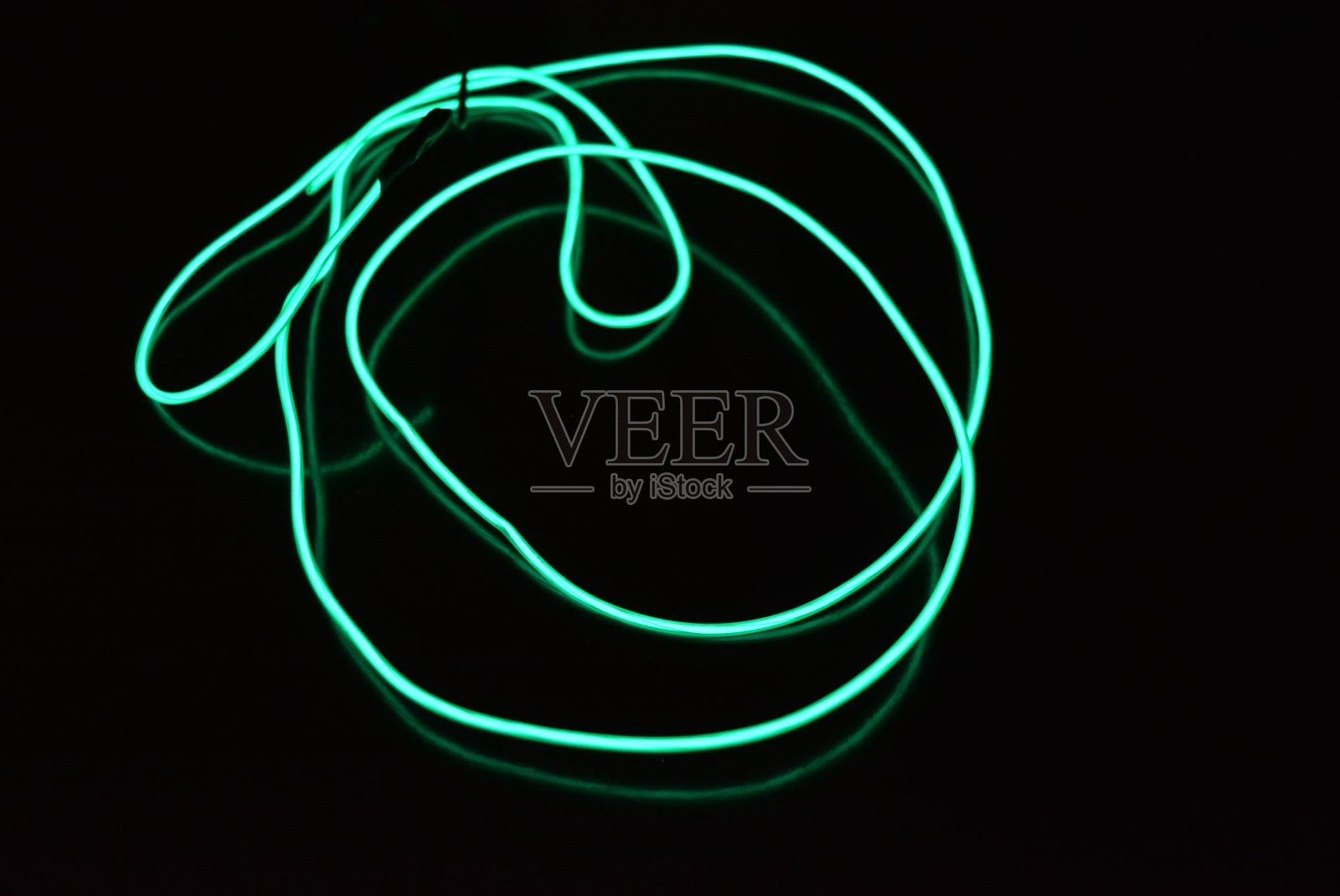 混乱的发光背景的电线和线路。扭曲纹理电致发光线给出了图像的特征。绿松石、蓝色和绿色灯，呈蛇形。照片摄影图片