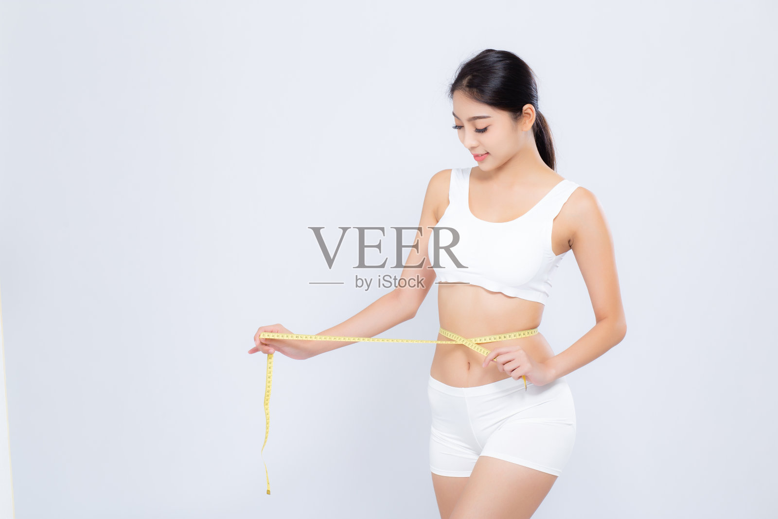 美丽的肖像亚洲妇女节食和苗条与测量腰围体重孤立在白色的背景，女孩有脂肪团和热量损失与卷尺，健康和健康的概念。照片摄影图片