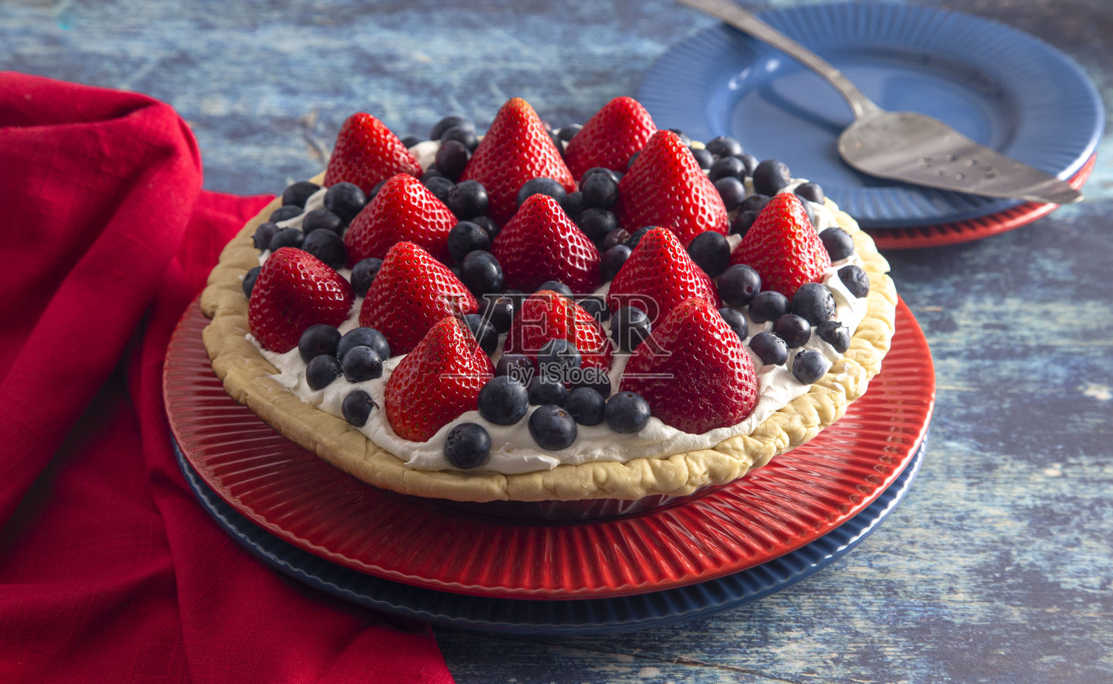 草莓和蓝莓新鲜夏季派在一个破旧的蓝色木制桌子上照片摄影图片