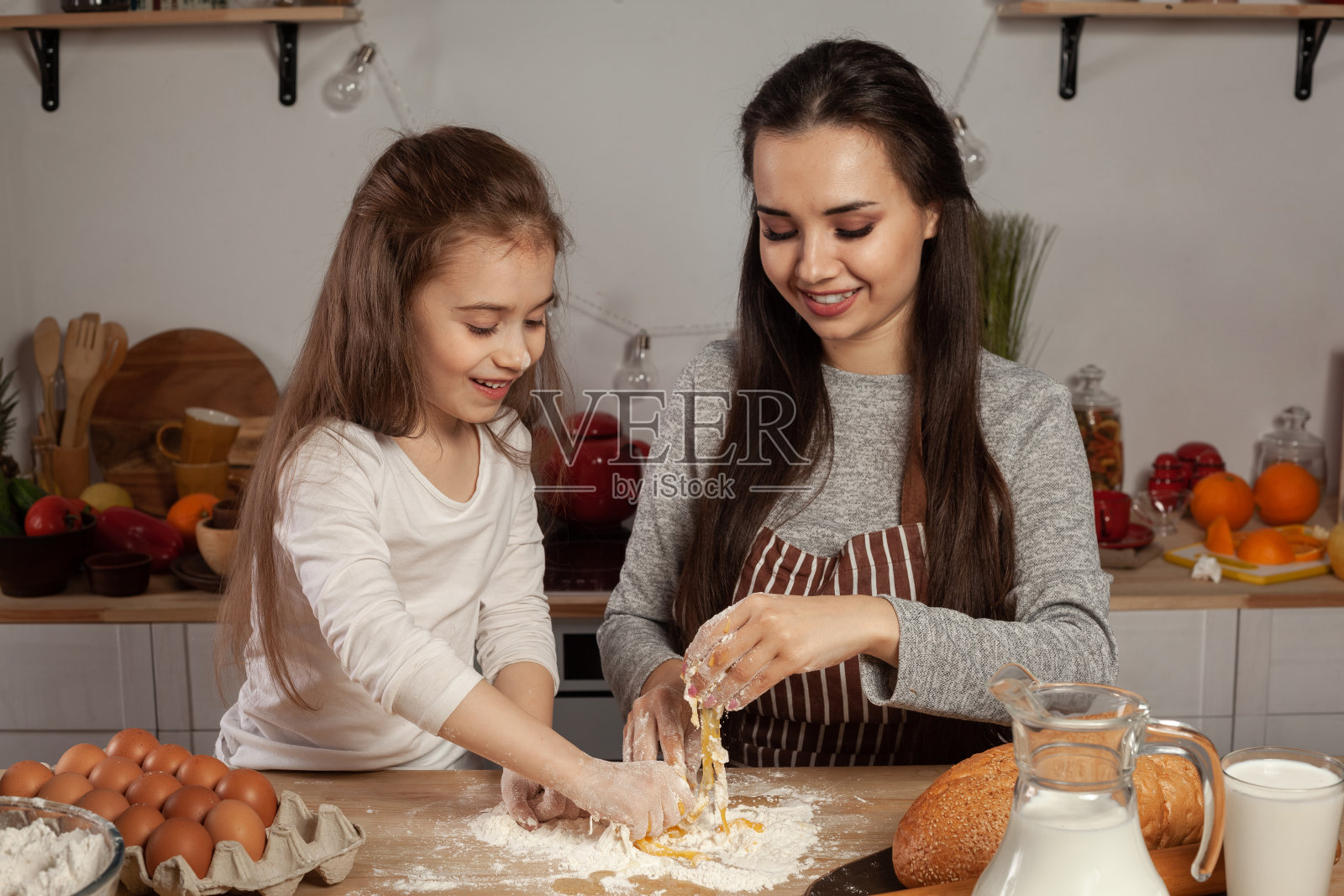 妈妈和她的女儿在厨房烤面包，玩得很开心照片摄影图片