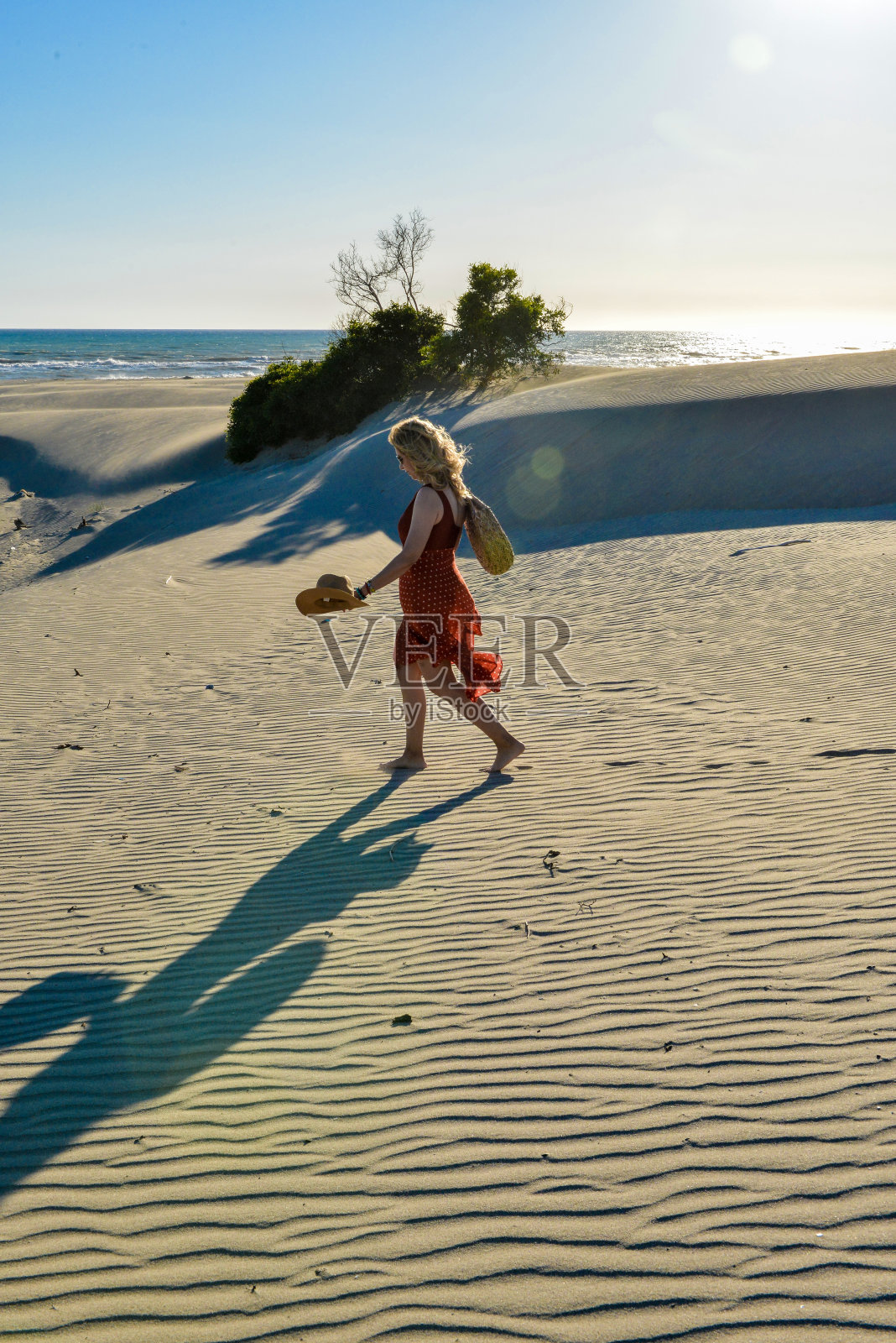 沙滩上的女人步行去海边。照片摄影图片