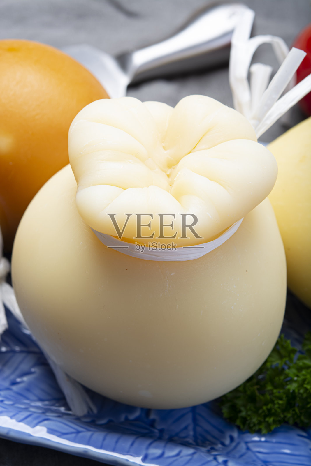 意大利波萝伏洛干酪泪滴状的陈年烟熏奶酪，放在靠近的蓝色盘子里照片摄影图片