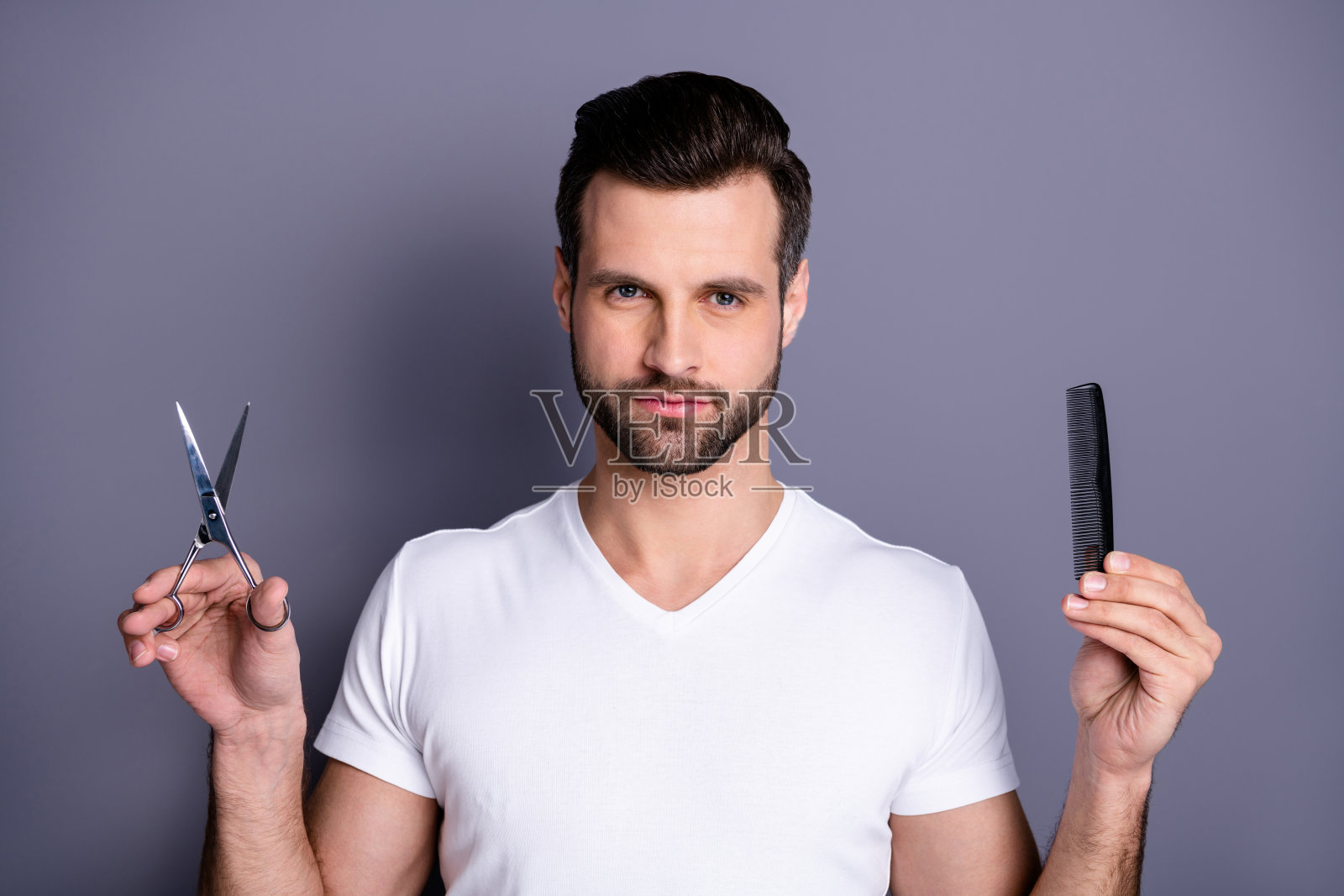 特写照片惊人的他，他，他的男子气概的理发店造型师，刷剪刀的手，看感兴趣的，好奇的顾客的发型准备做杰作穿休闲的白色t恤孤立的灰色背景照片摄影图片