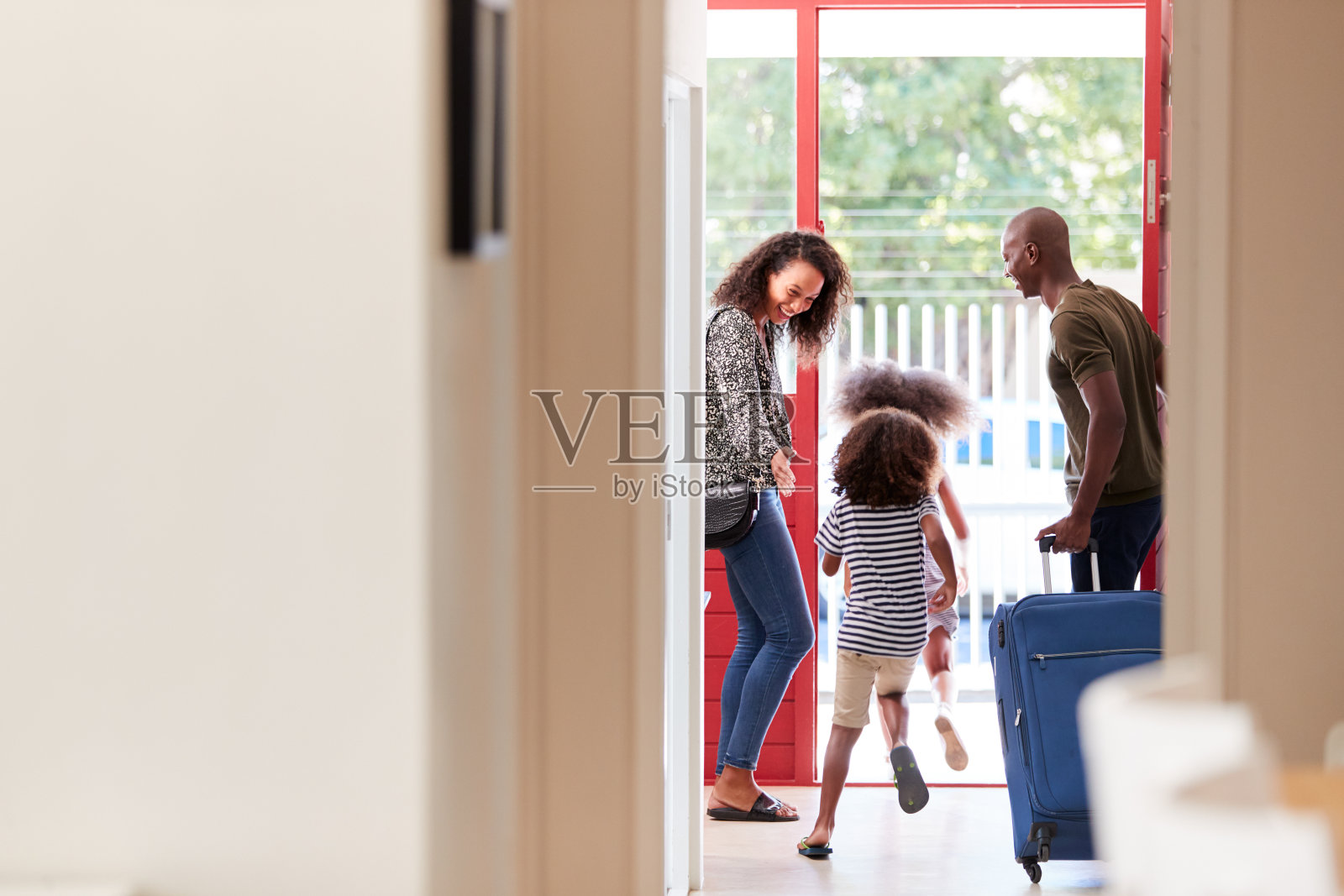 一家人拿着箱子站在前门准备去度假照片摄影图片