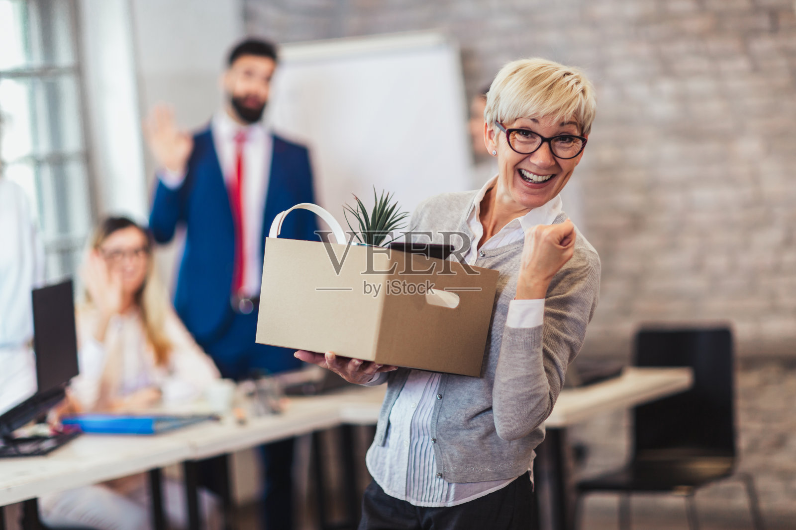 年老的雇员带着装满物品的箱子离开办公室。退休的时间照片摄影图片