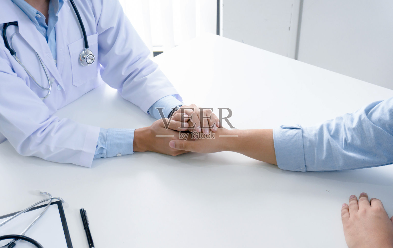 医生牵着病人的手，安慰他的男病人帮助的手的概念。照片摄影图片