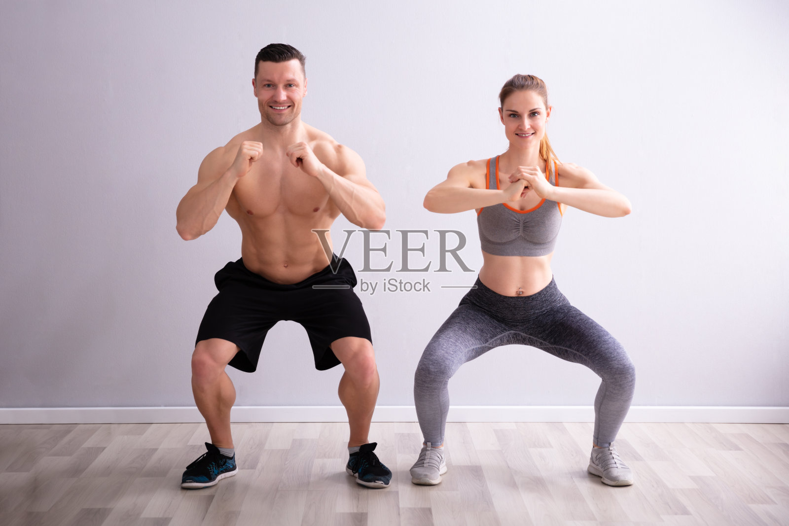 健身夫妇穿着运动服在健身房做下蹲练习照片摄影图片