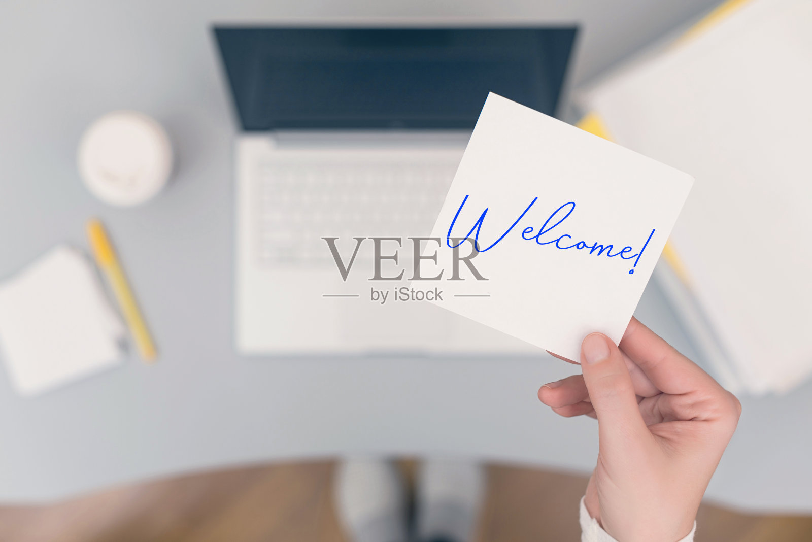 女职员坐着，拿着纸贴纸，上面写着“欢迎光临”。经营理念。的概念。照片摄影图片