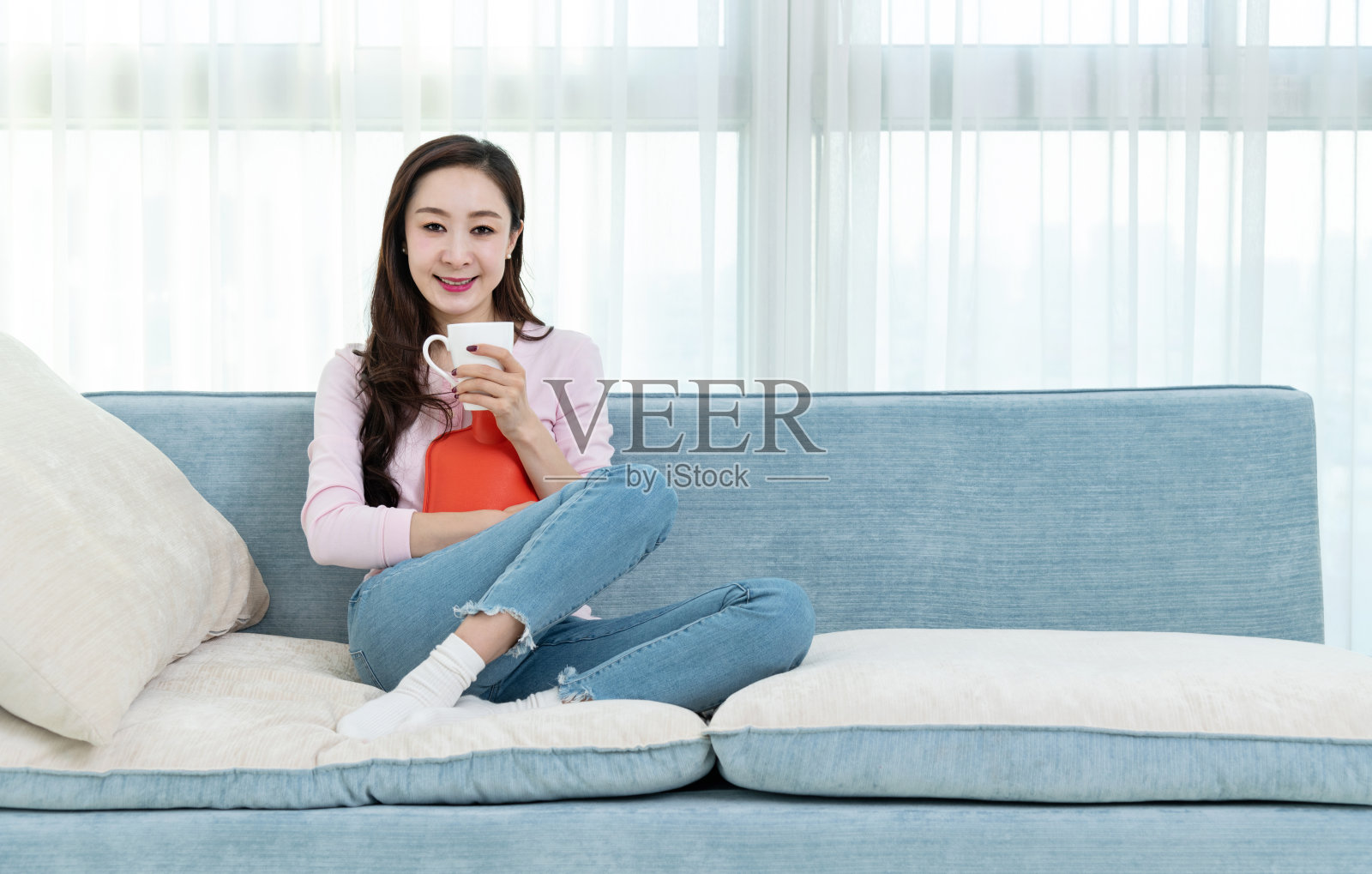 女人坐在沙发上，拿着热水瓶照片摄影图片