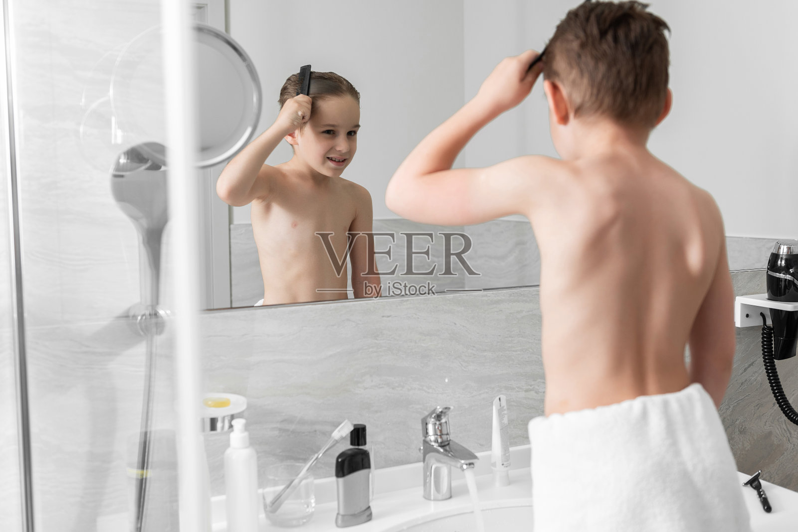 小男孩微笑着在浴室里梳理照片摄影图片