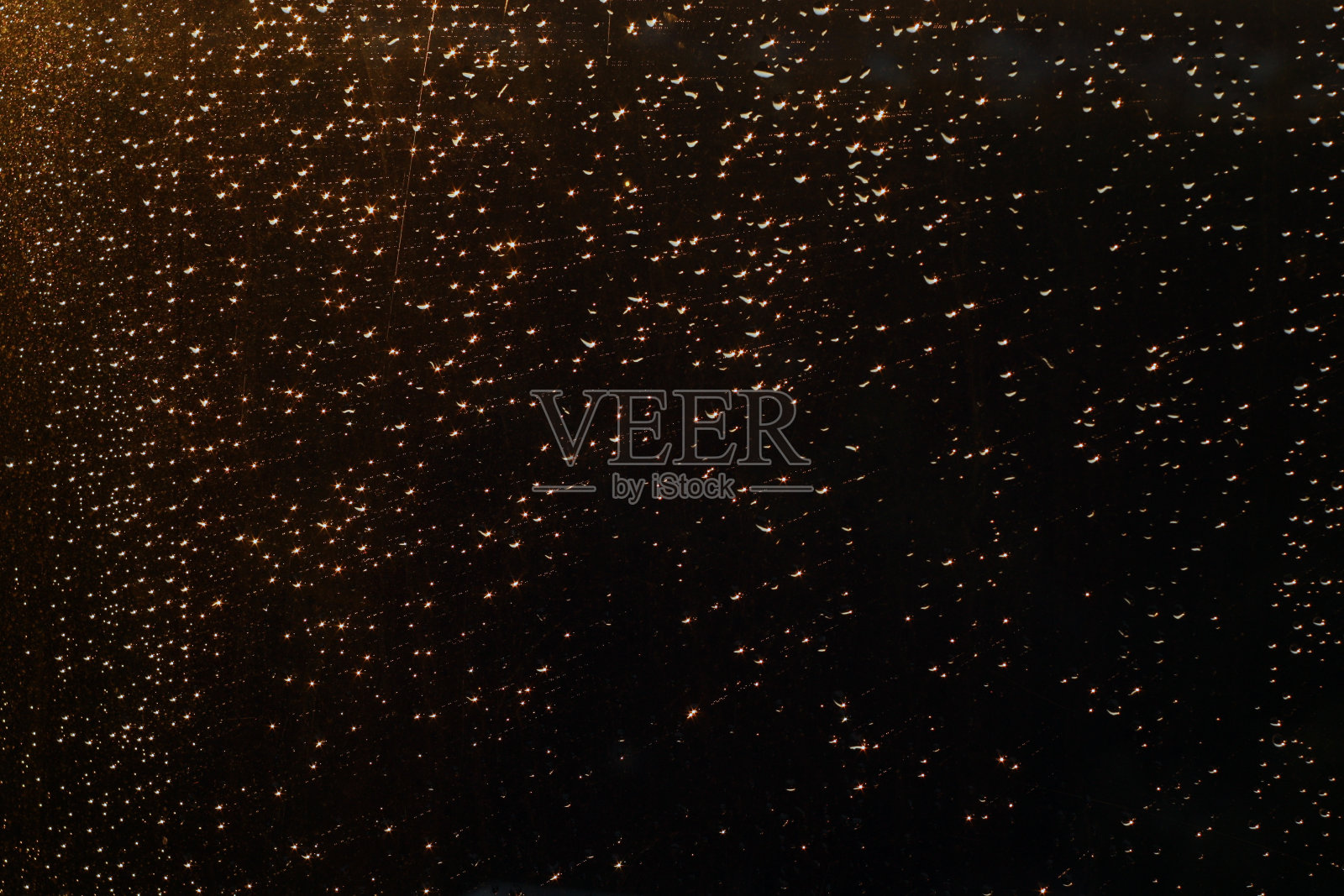 雨点落在窗户上，夕阳的灯光散了。照片摄影图片