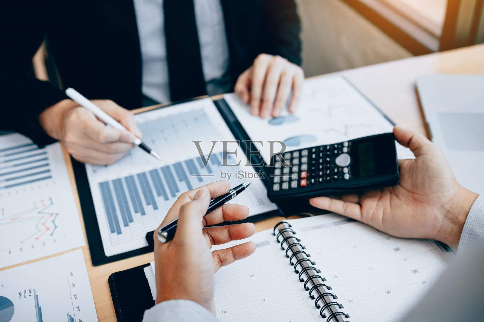 两个商人在办公室的桌子上讨论分析分享关于公司预算和财务计划的计算。照片摄影图片