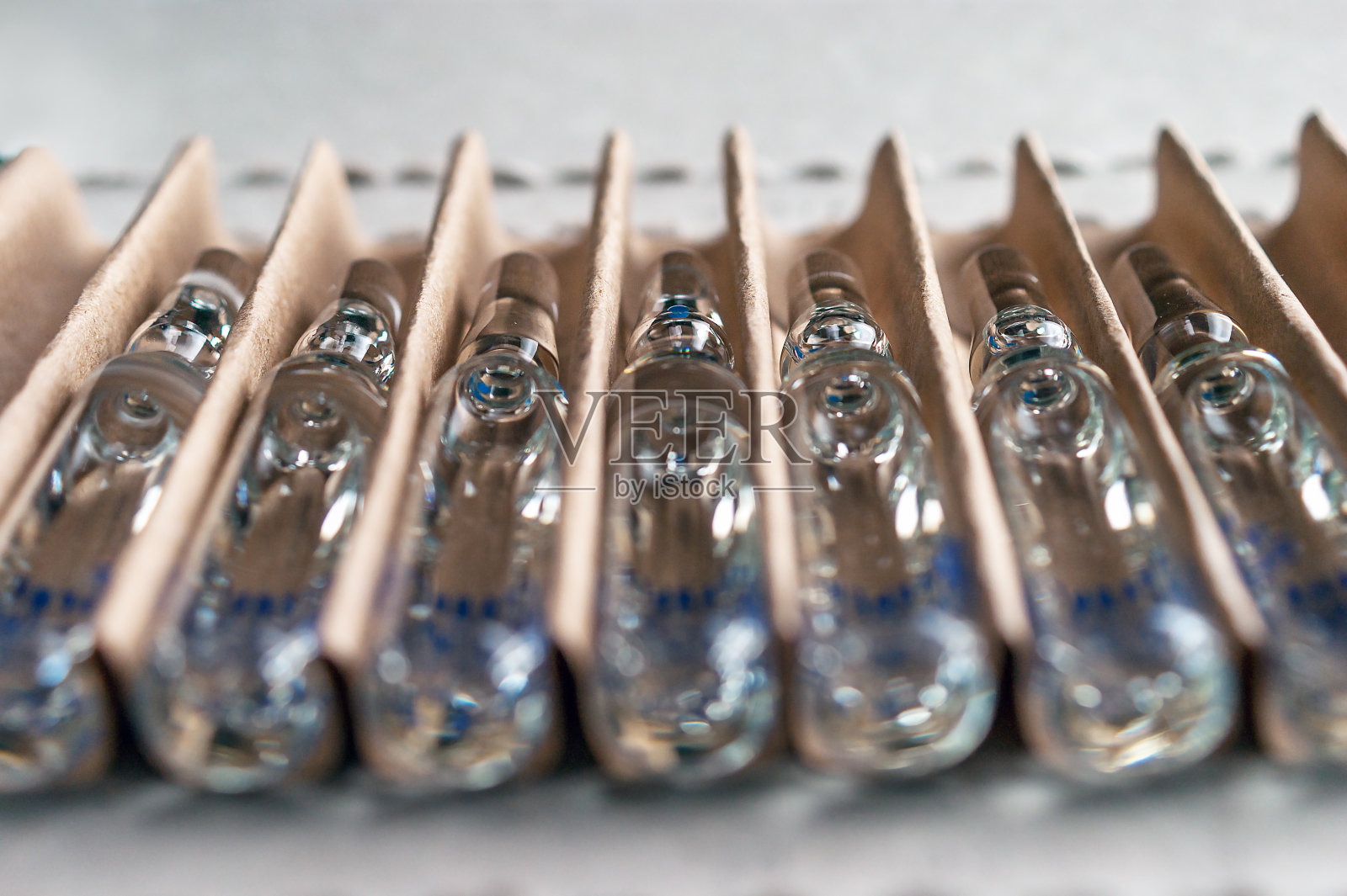 透视近景透明玻璃安瓿与液体药物在纸板包装。照片摄影图片