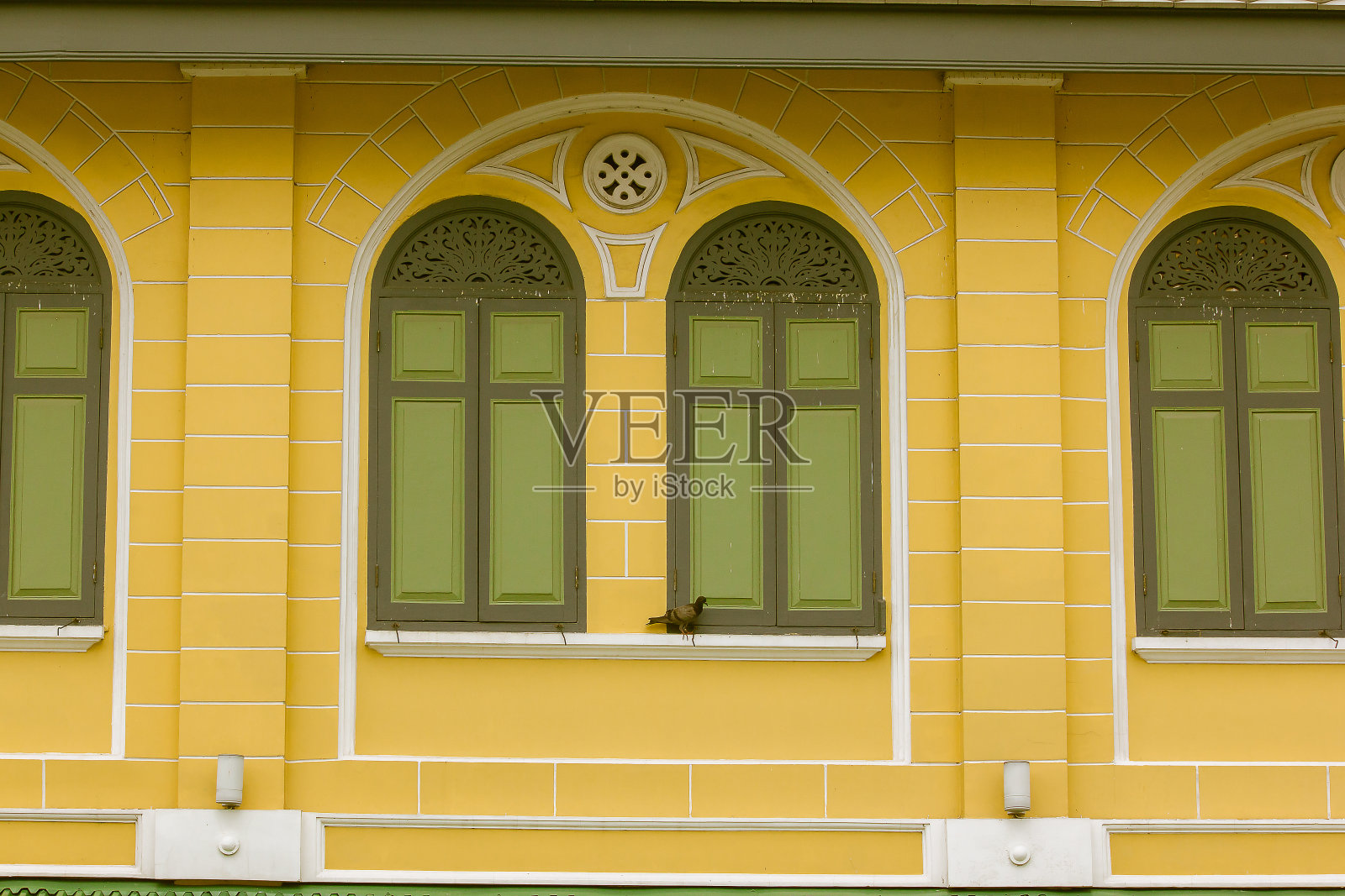 绿色的窗户在橙色的墙上。照片摄影图片