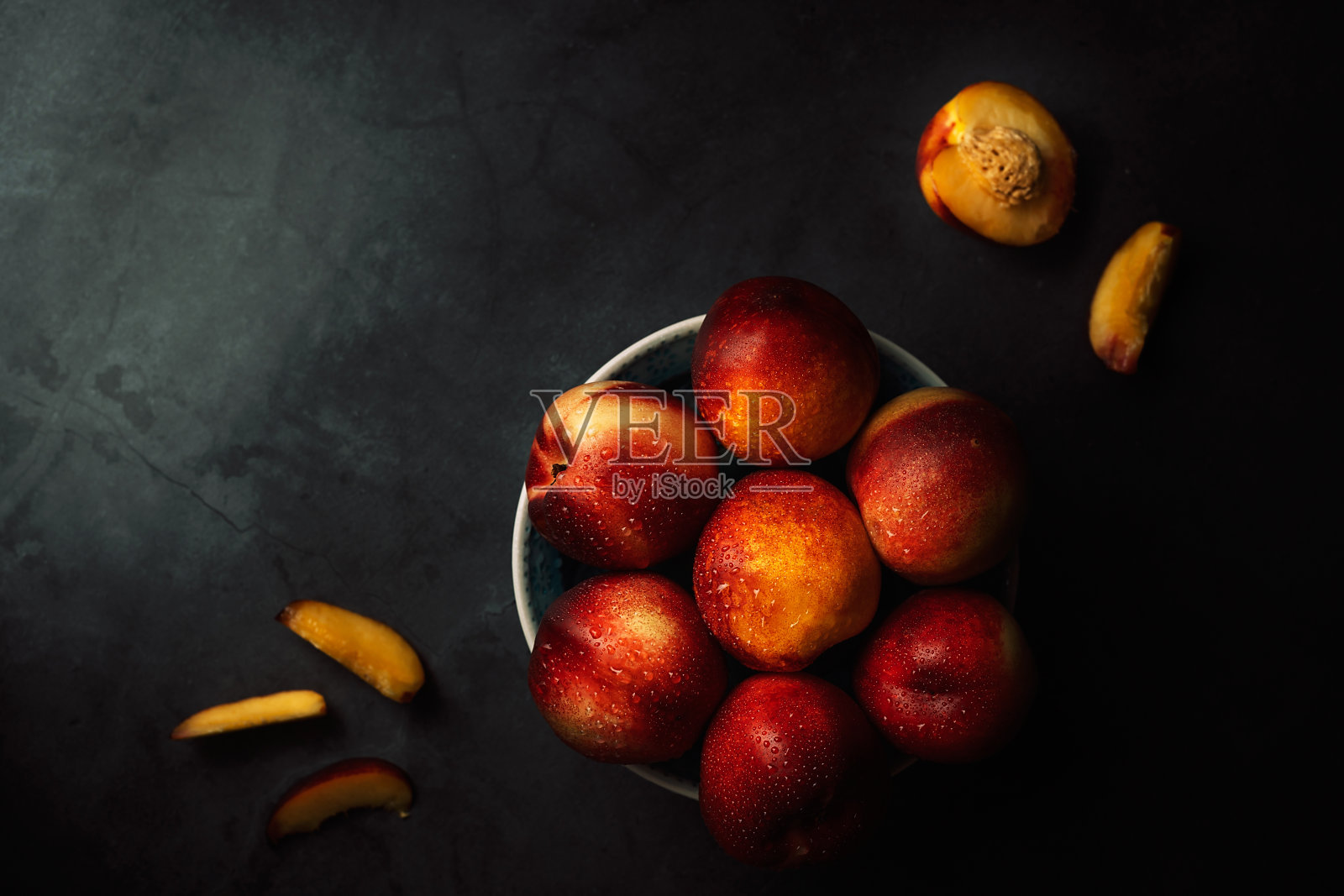 新鲜油桃与水滴在一个碗在黑暗的背景生活。低调。照片摄影图片