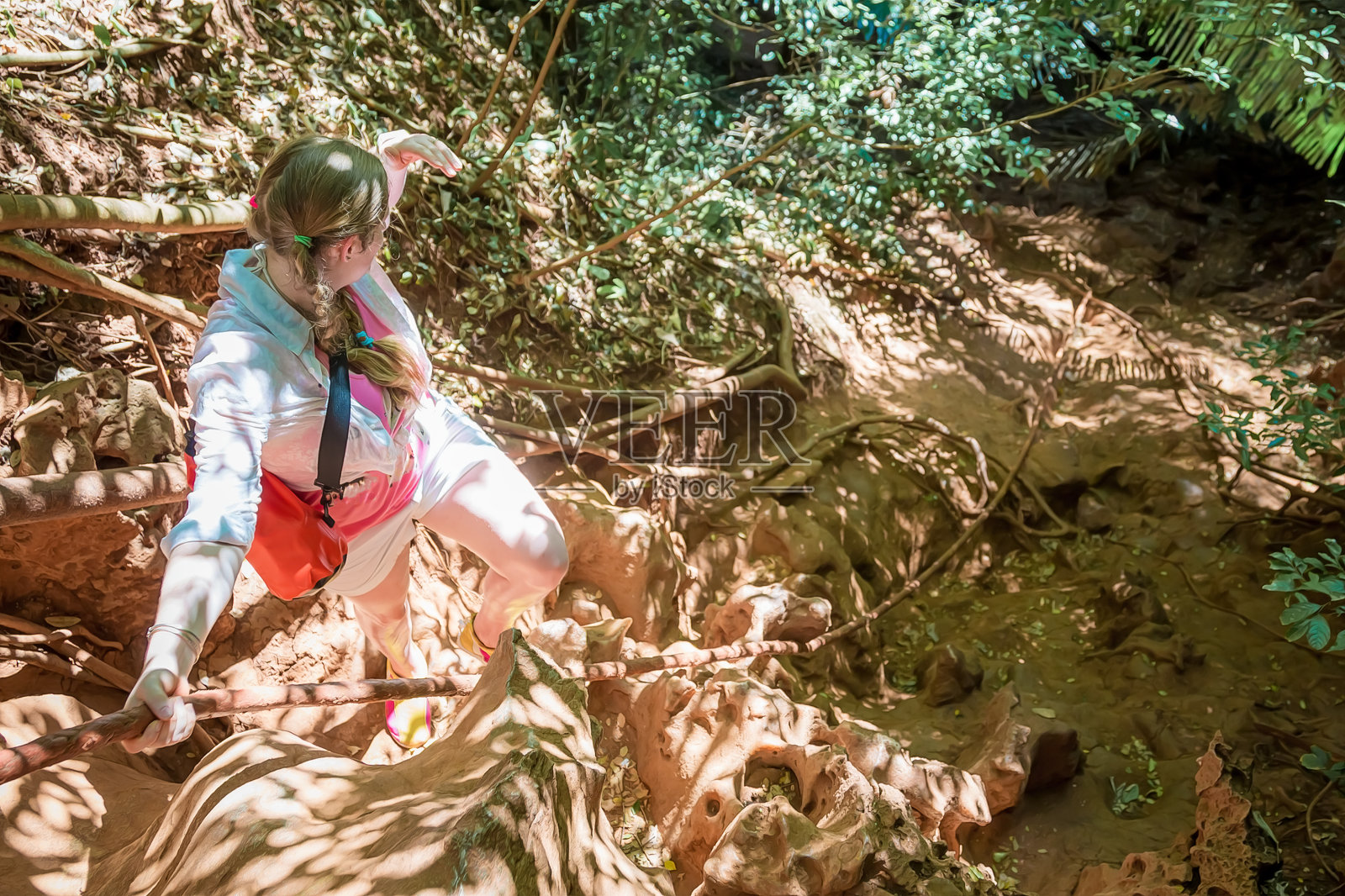 一个穿白色衣服的年轻女孩在绷紧的绳索上攀登这座山。从以上观点。在热带丛林中，一位妇女遥望远方。照片摄影图片