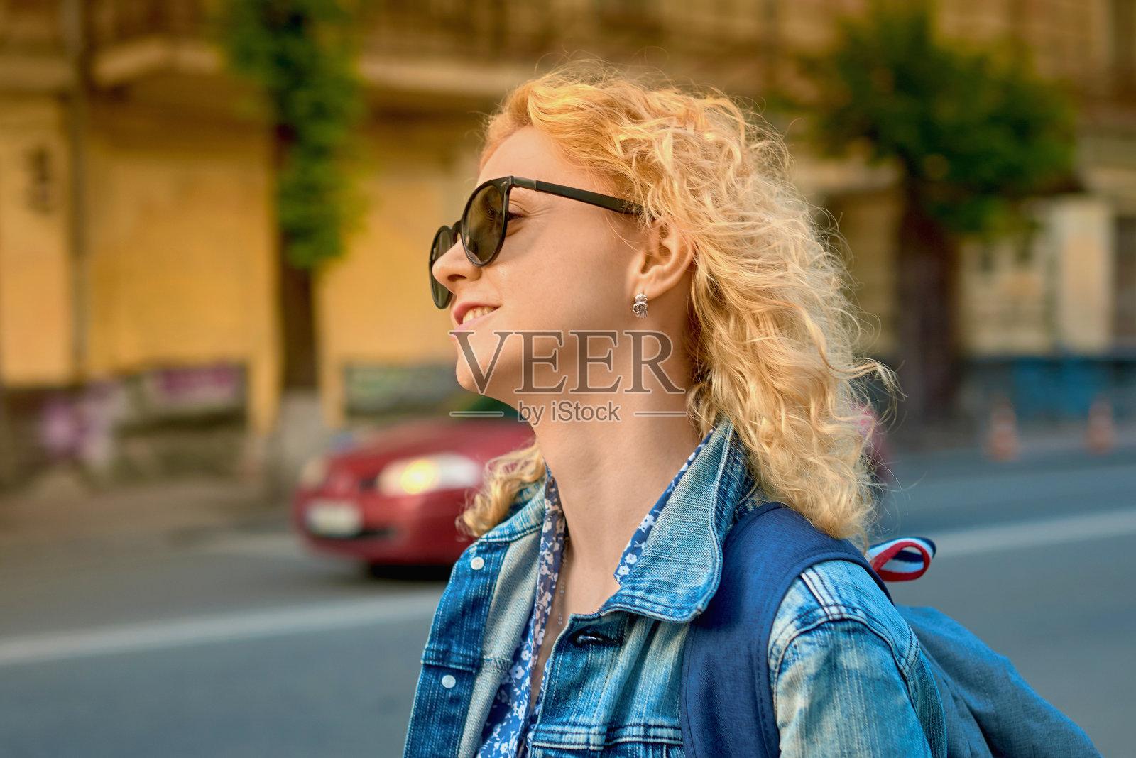 年轻迷人的卷发生活女子在城市风景的背景照片摄影图片