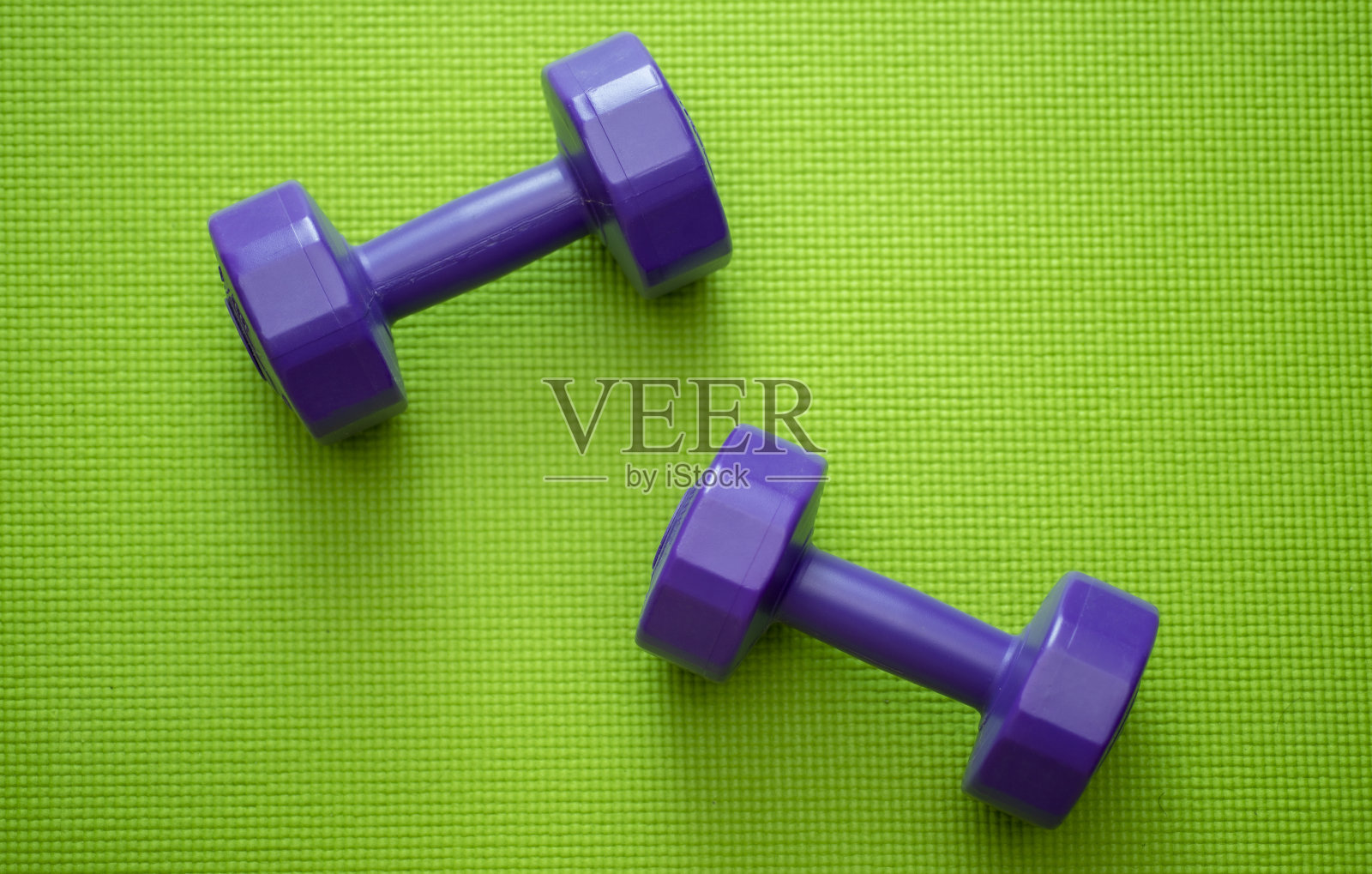 瑜伽垫上的紫色哑铃用于锻炼。照片摄影图片