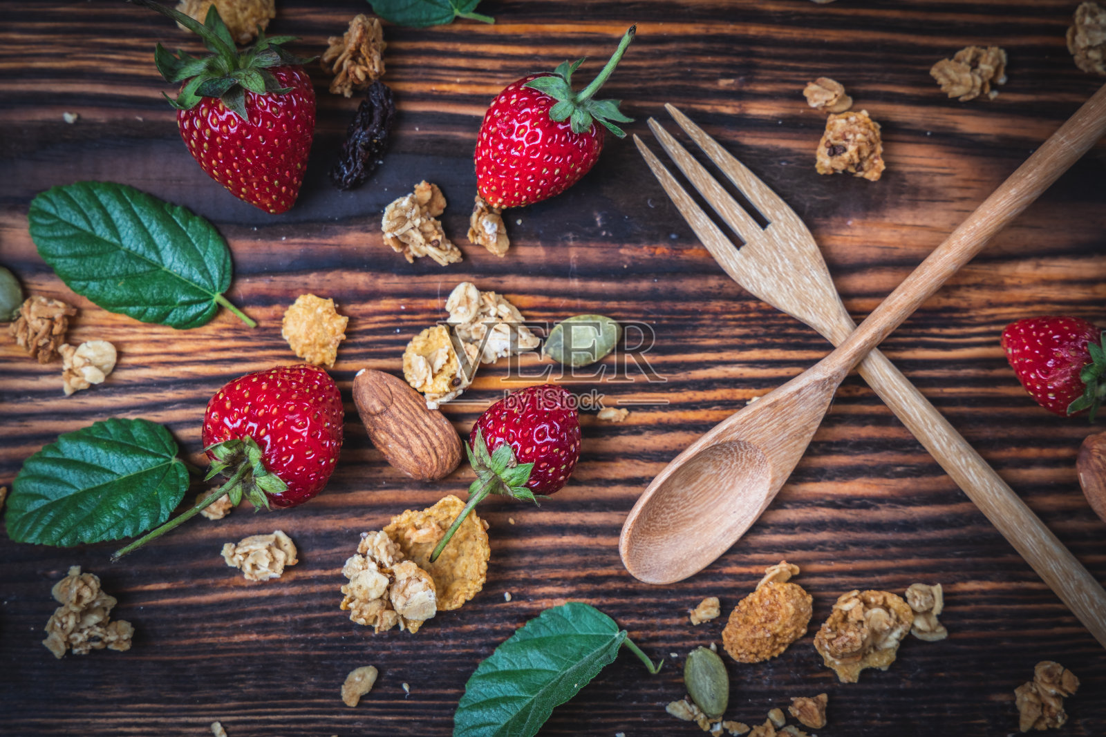 俯视图浆果和cranola谷物放在木地板上用勺子，素食或健康食品的概念。照片摄影图片