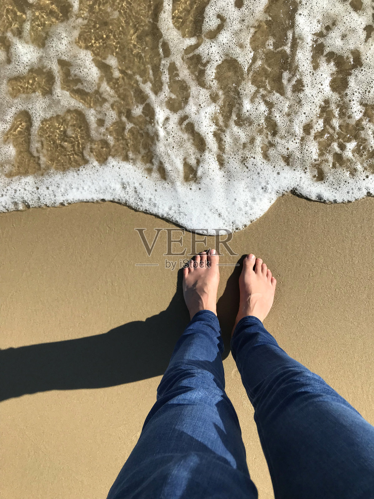英国，英国，多塞特，伯恩茅斯海滩，阳光明媚的日子里，白色的英国人的脚在金色的沙滩上被海浪拍打着海岸线，赤脚用脚趾走路，海边的脚印站在带有泡沫的海滩上照片摄影图片