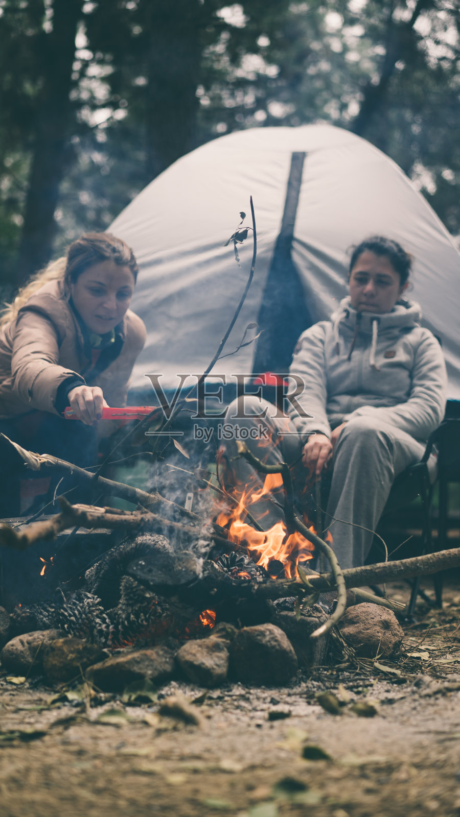 两个女人坐在露营帐篷前玩篝火照片摄影图片