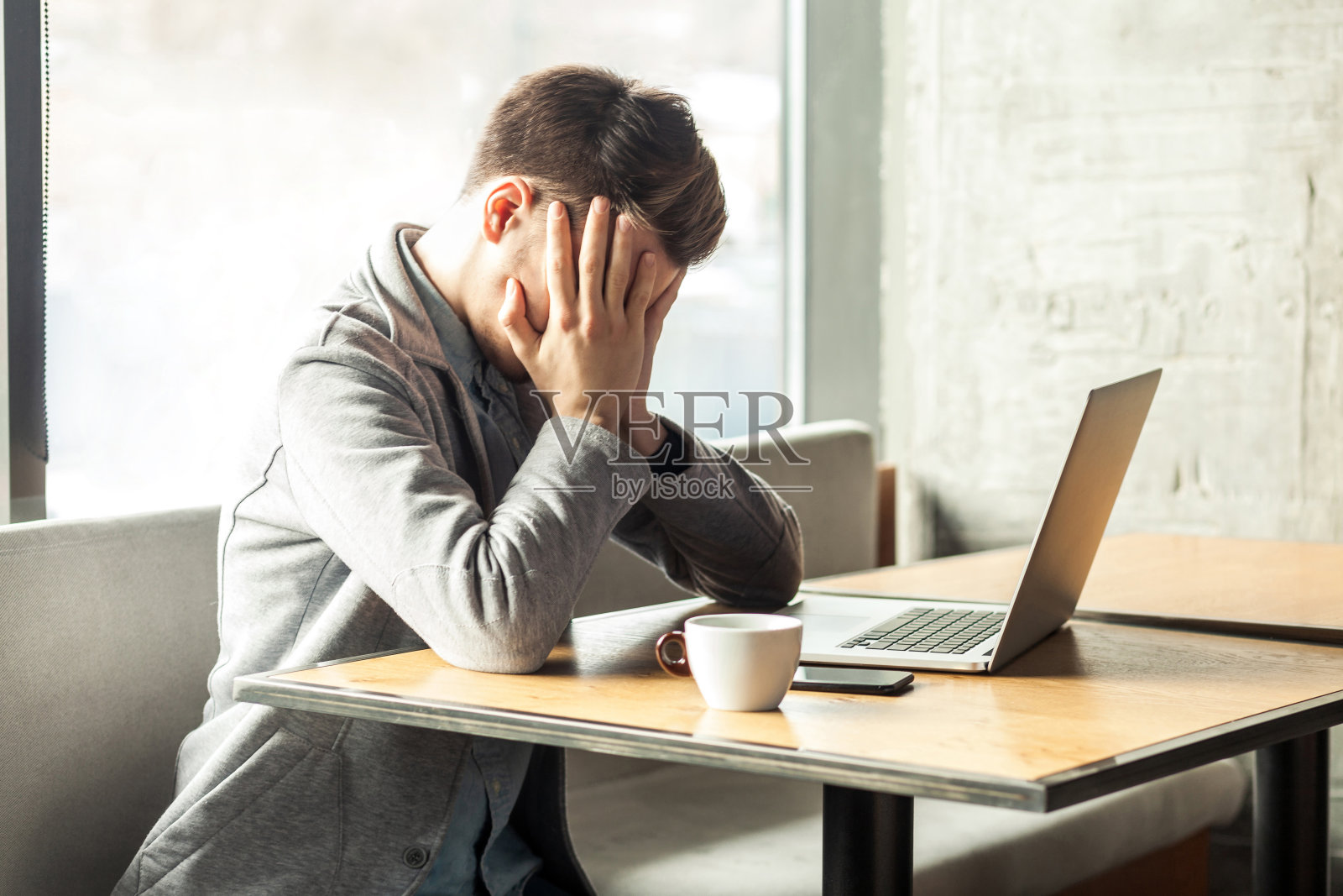 疲惫的年轻自由职业者在咖啡馆用笔记本电脑寻找工作照片摄影图片