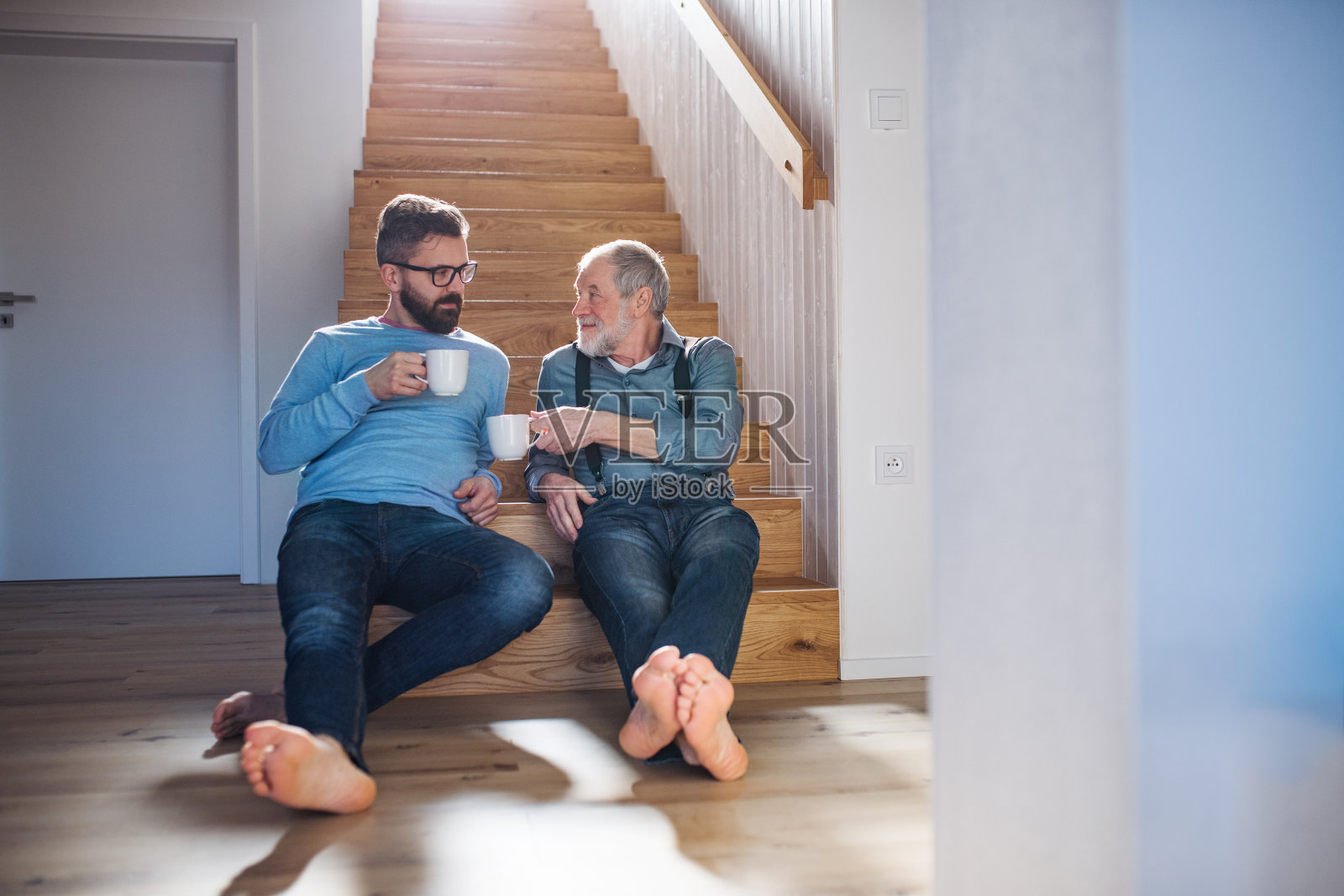 一个成年潮人的儿子和一个年长的父亲坐在家里的楼梯上聊天。照片摄影图片