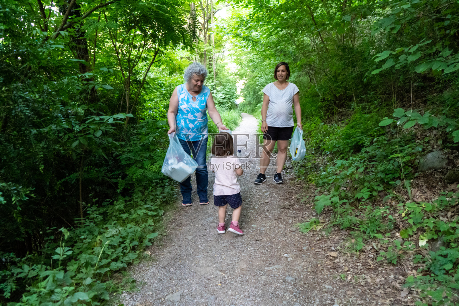 小女孩，怀孕的母亲和祖母正在清理塑料森林照片摄影图片