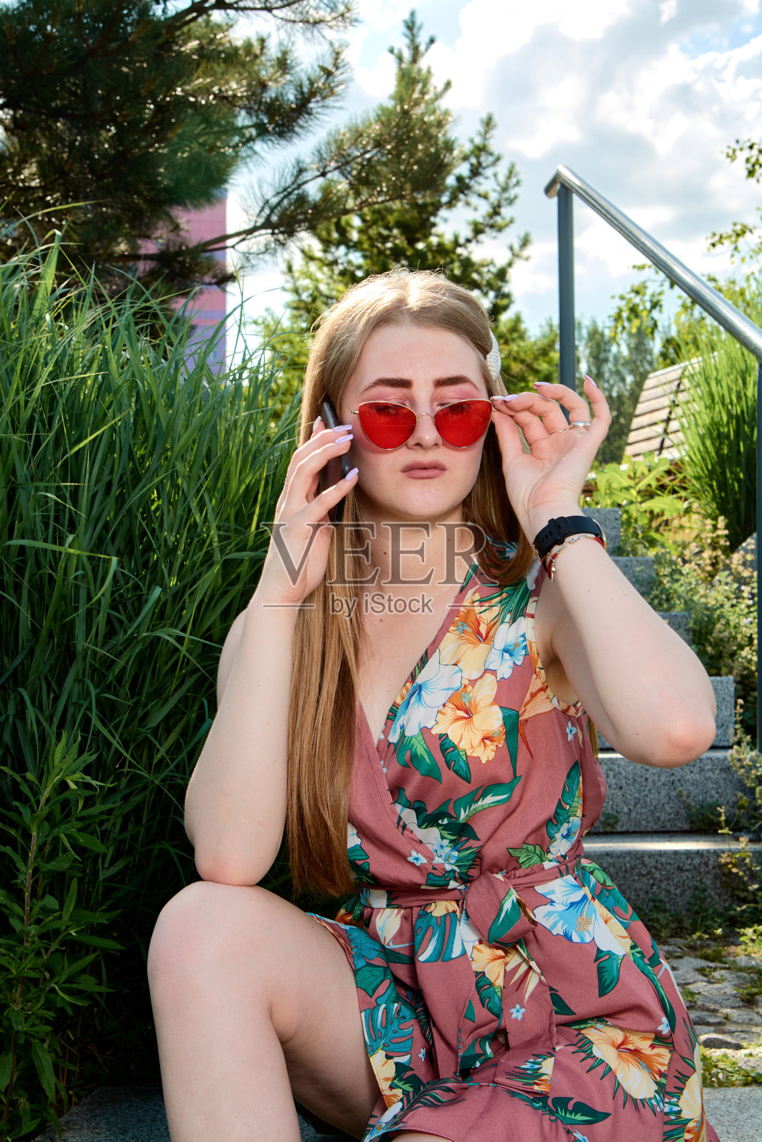 年轻有魅力的女人。红色太阳镜，彩色连衣裙，手机，5G, 4G, 3G, 2G, LTE网络。照片摄影图片