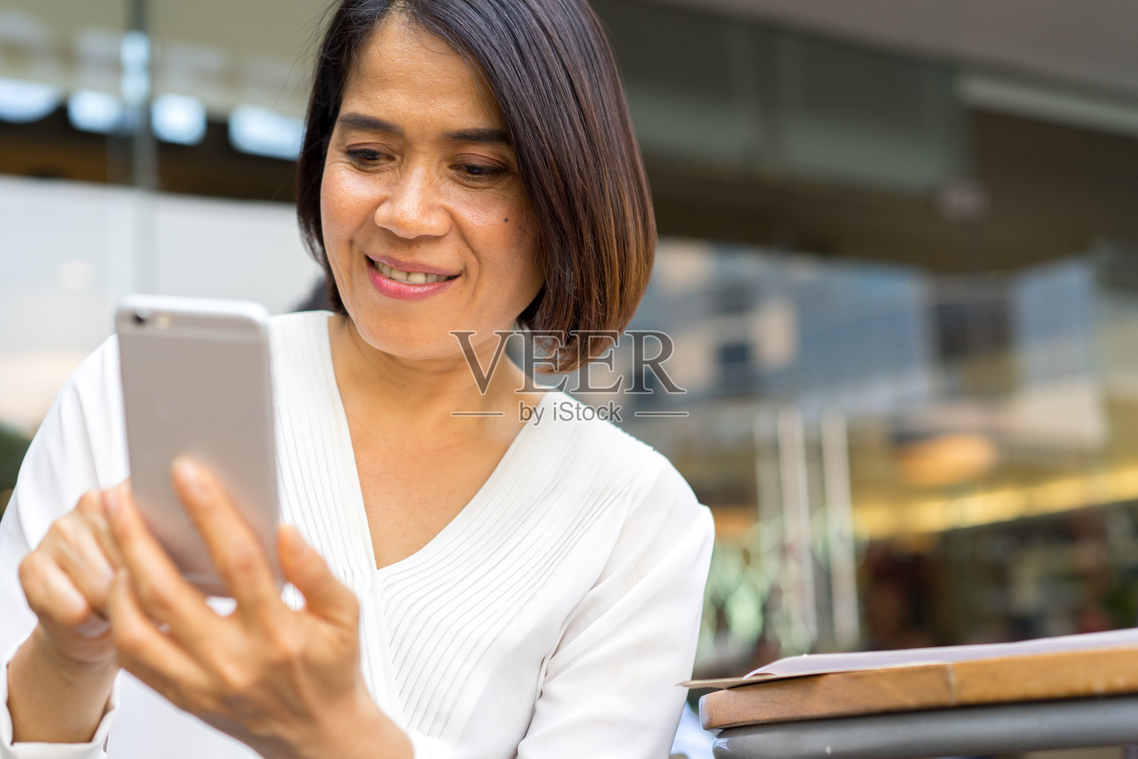 近距离观察成熟的亚洲女性在周末手持智能手机使用应用程序或在网站上观看媒体，以科技理念放松生活方式照片摄影图片