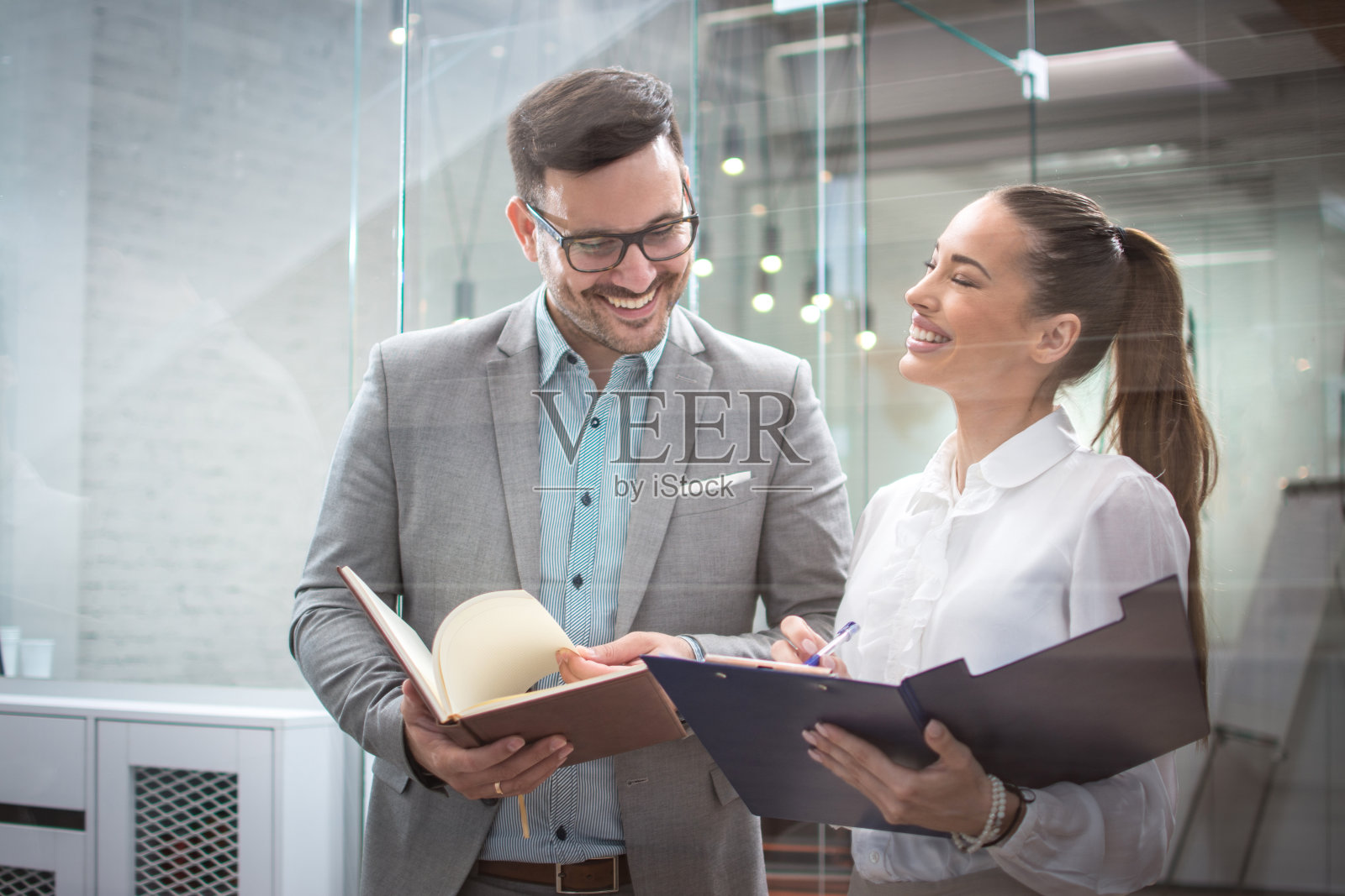 两个开朗、有魅力的年轻商人在办公室见面有说有笑照片摄影图片