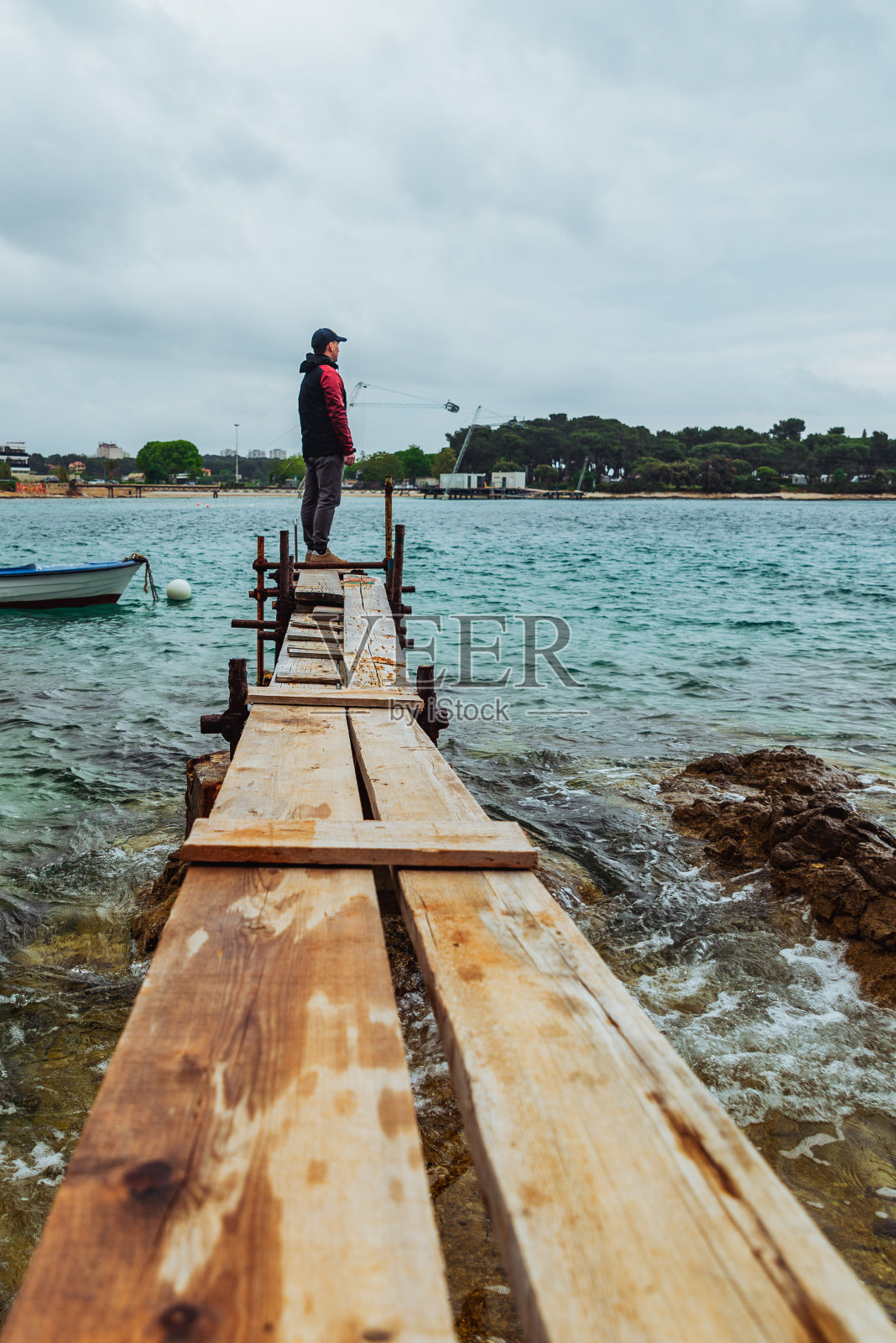 一个人站在小渔码头边，望着波涛汹涌的大海照片摄影图片