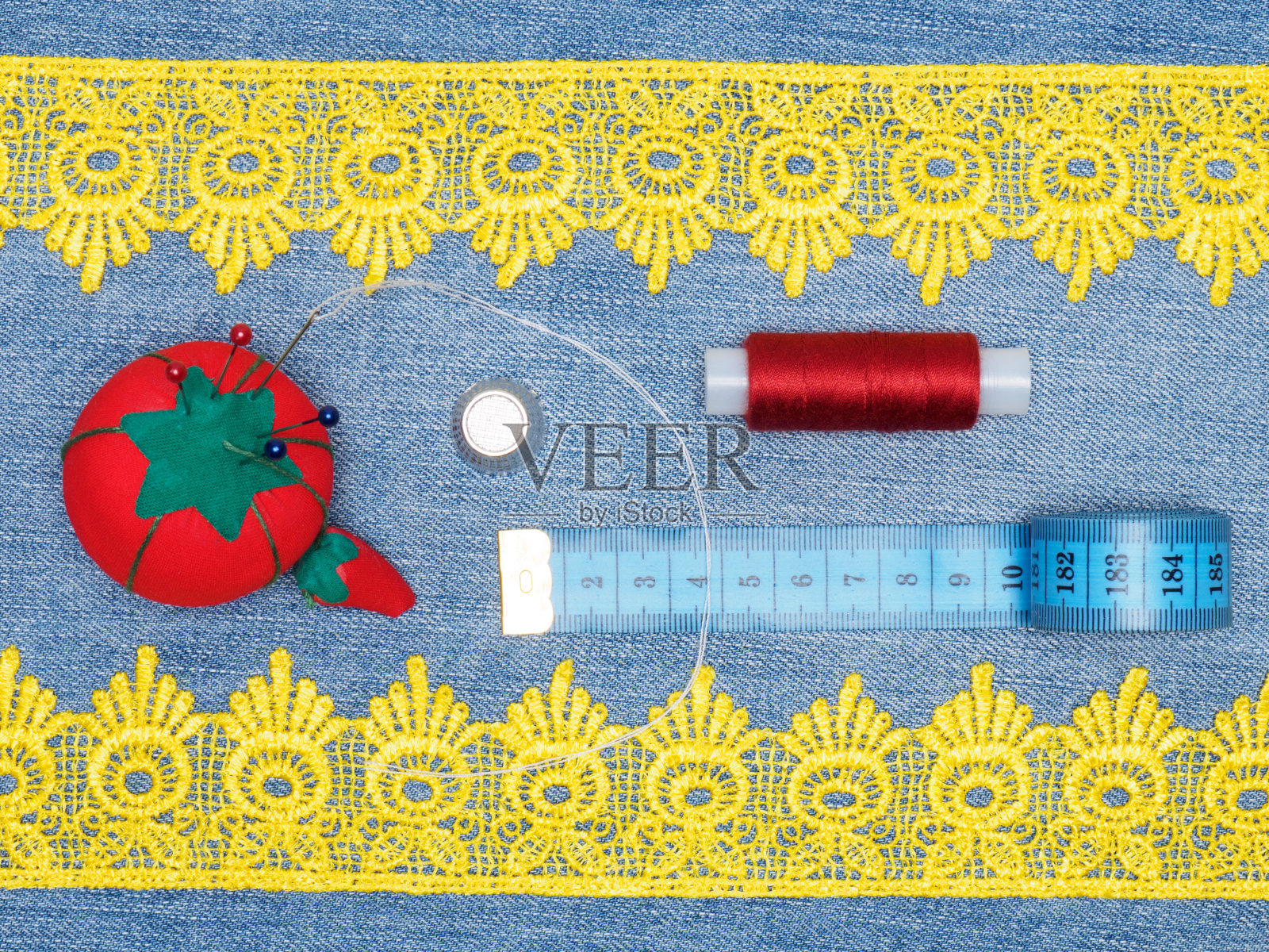 黄色花边，顶针，针垫，线，卷尺在牛仔裤的背景。缝纫静物照片摄影图片