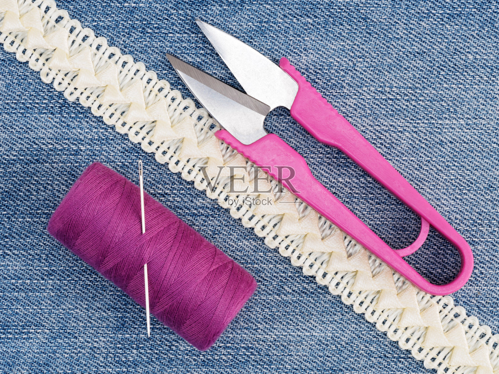 米色花边，线，针，剪刀在牛仔裤的背景。缝纫静物照片摄影图片