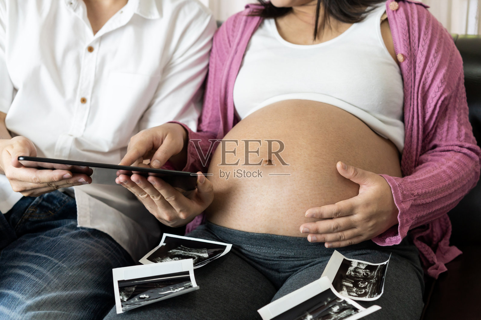 怀孕夫妇在家里感受到爱和放松。照片摄影图片