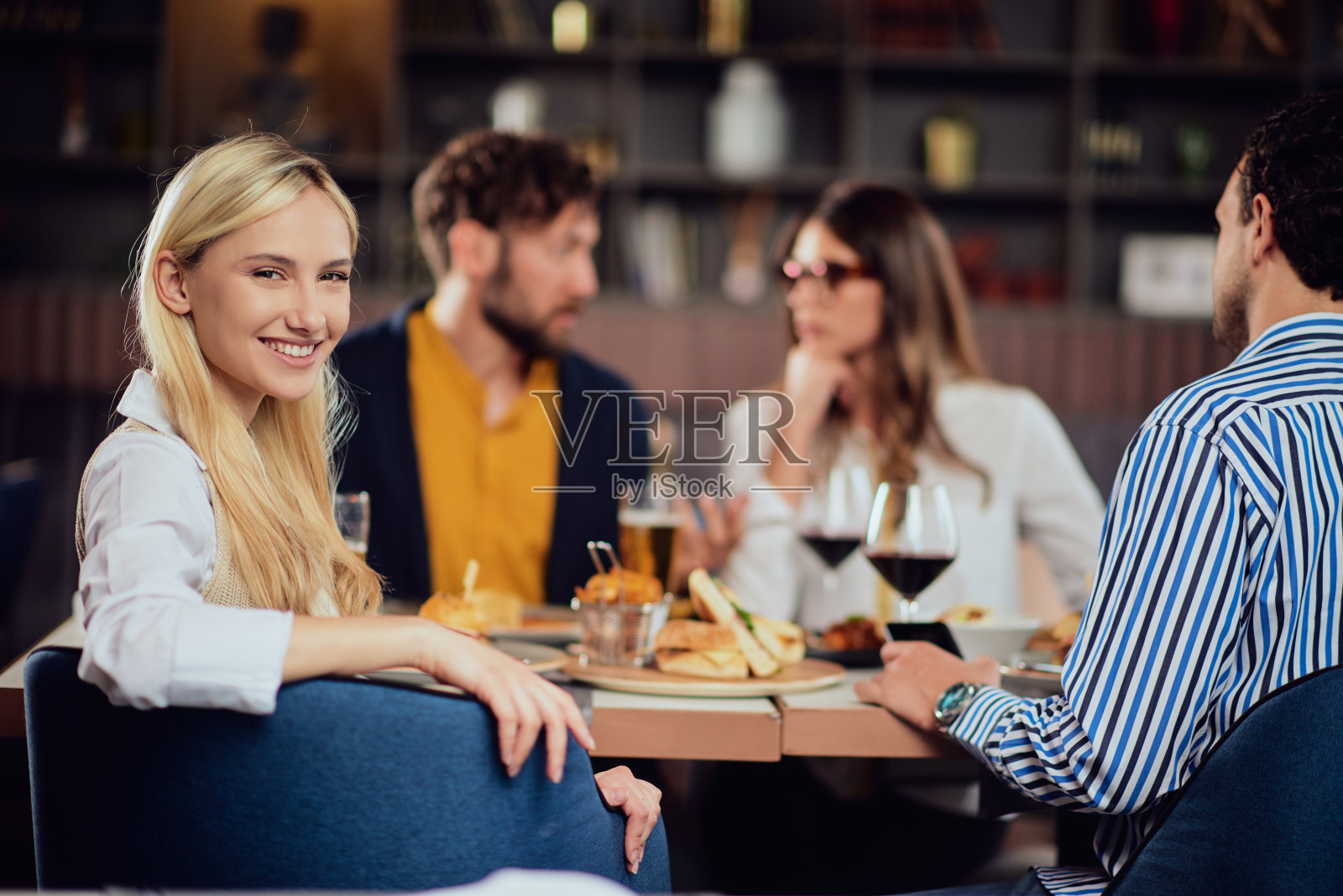 一个女人和她的朋友坐在餐馆里向后看。照片摄影图片