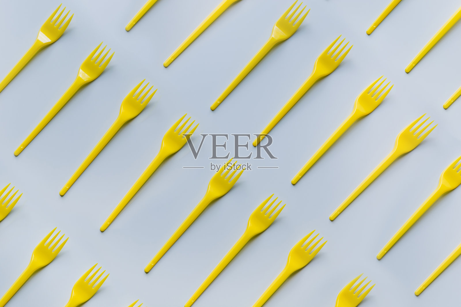 一次性野餐用的黄色叉子在灰色对角线上。前视图。平的。照片摄影图片